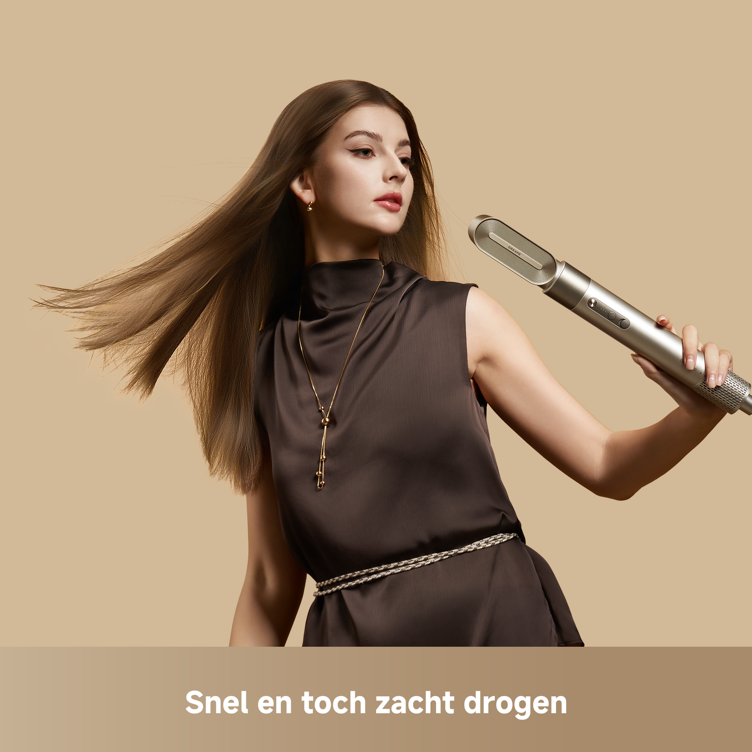 Vrouw met lang bruin haar houdt zilveren föhn vast, bruine jurk, beige achtergrond.
