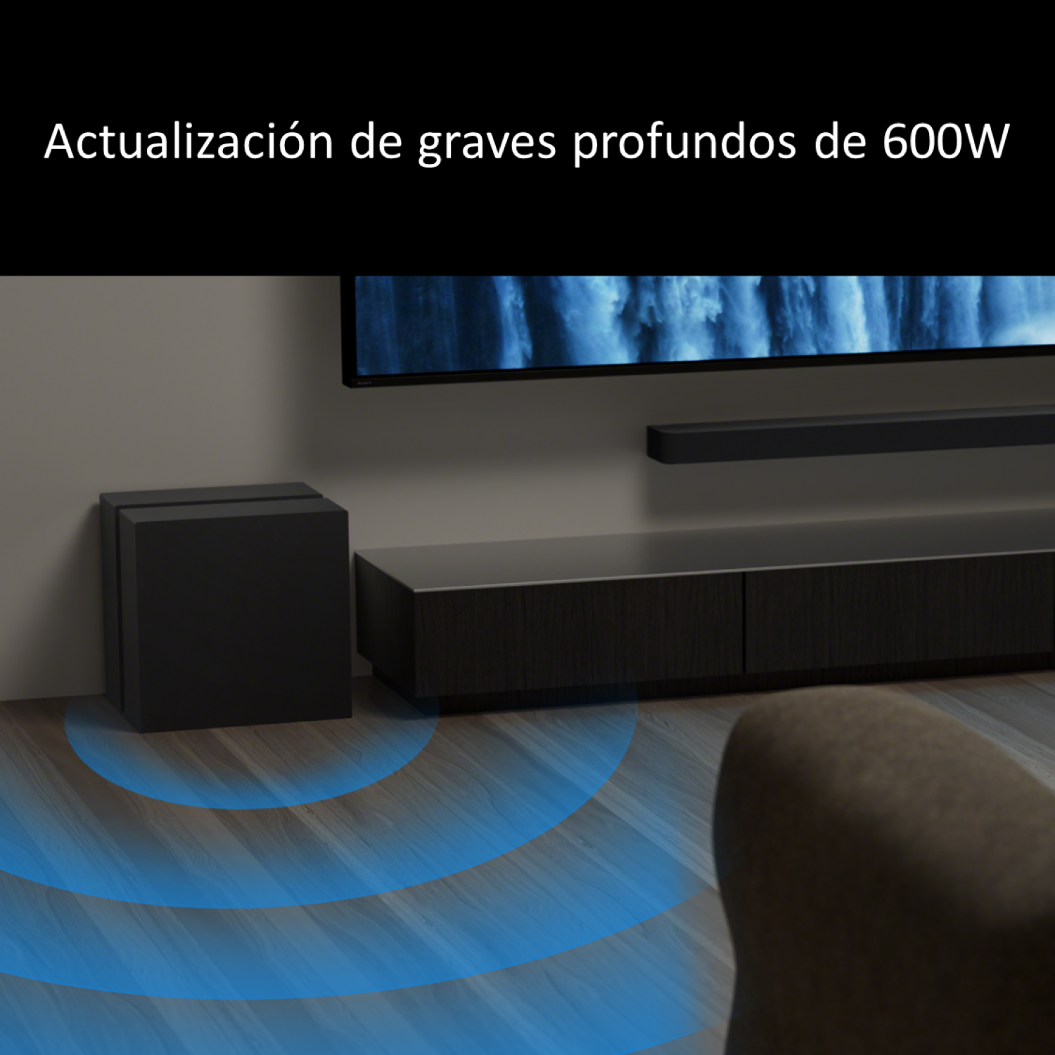 Subwoofer negro emitiendo ondas sonoras azules sobre suelo de madera frente a un TV.