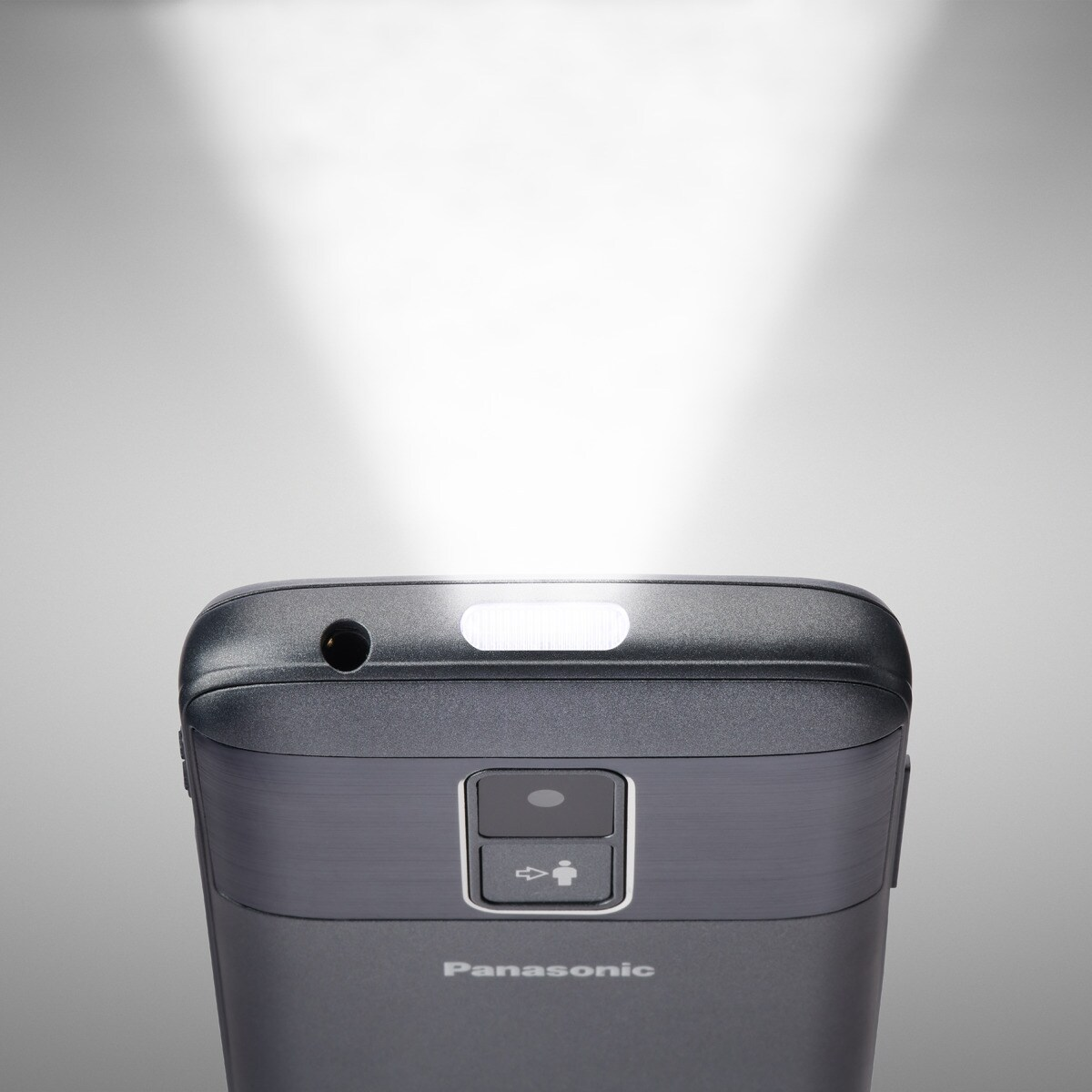 Parte superior de un teléfono oscuro con el flash encendido y una cámara.