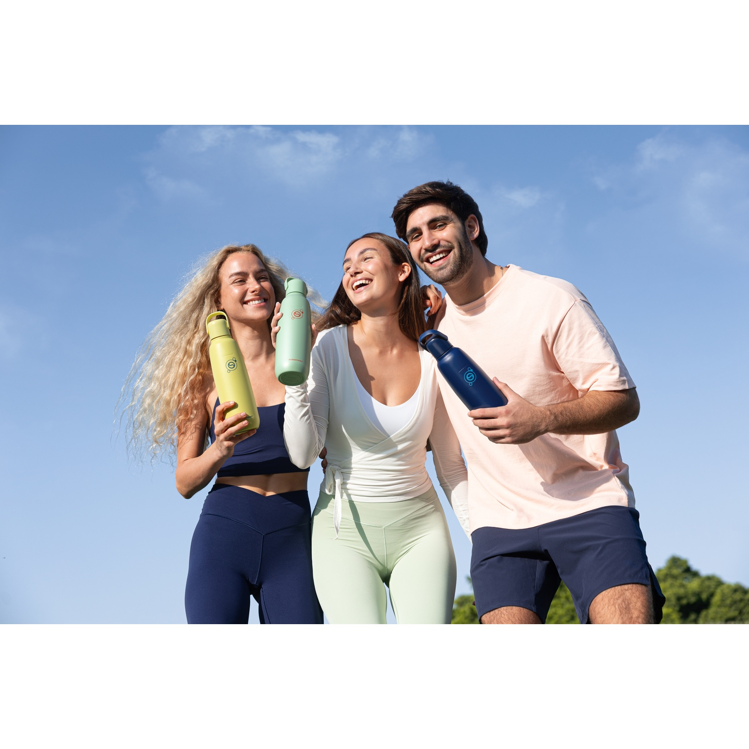 Trois personnes tenant des bouteilles d'eau dehors sous un ciel bleu.