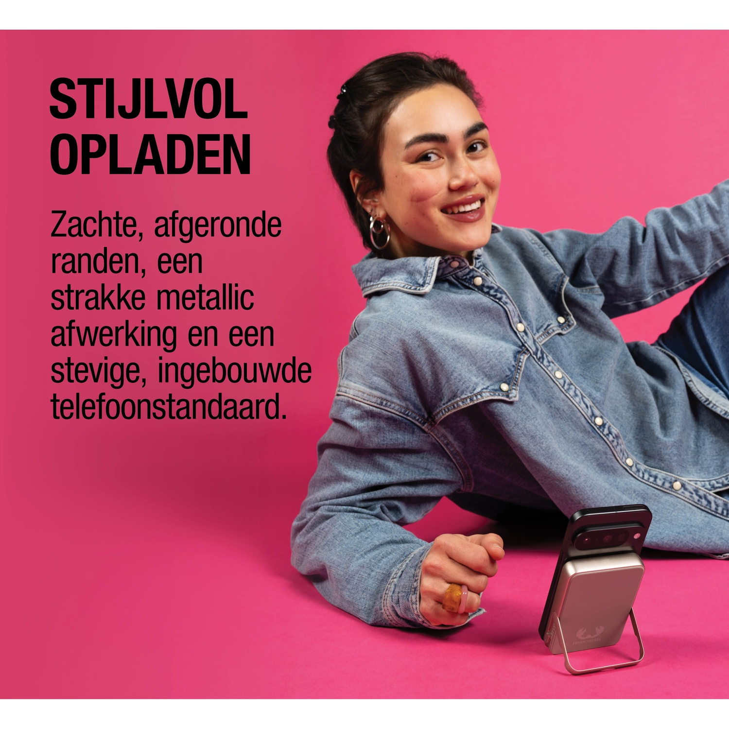 Een vrouw ligt op een roze achtergrond met een telefoonoplader.