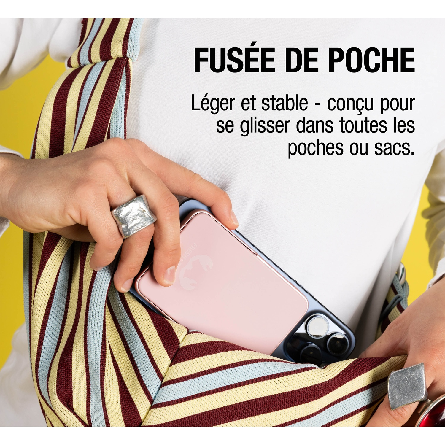 Une personne glisse un smartphone rose dans un sac à rayures.