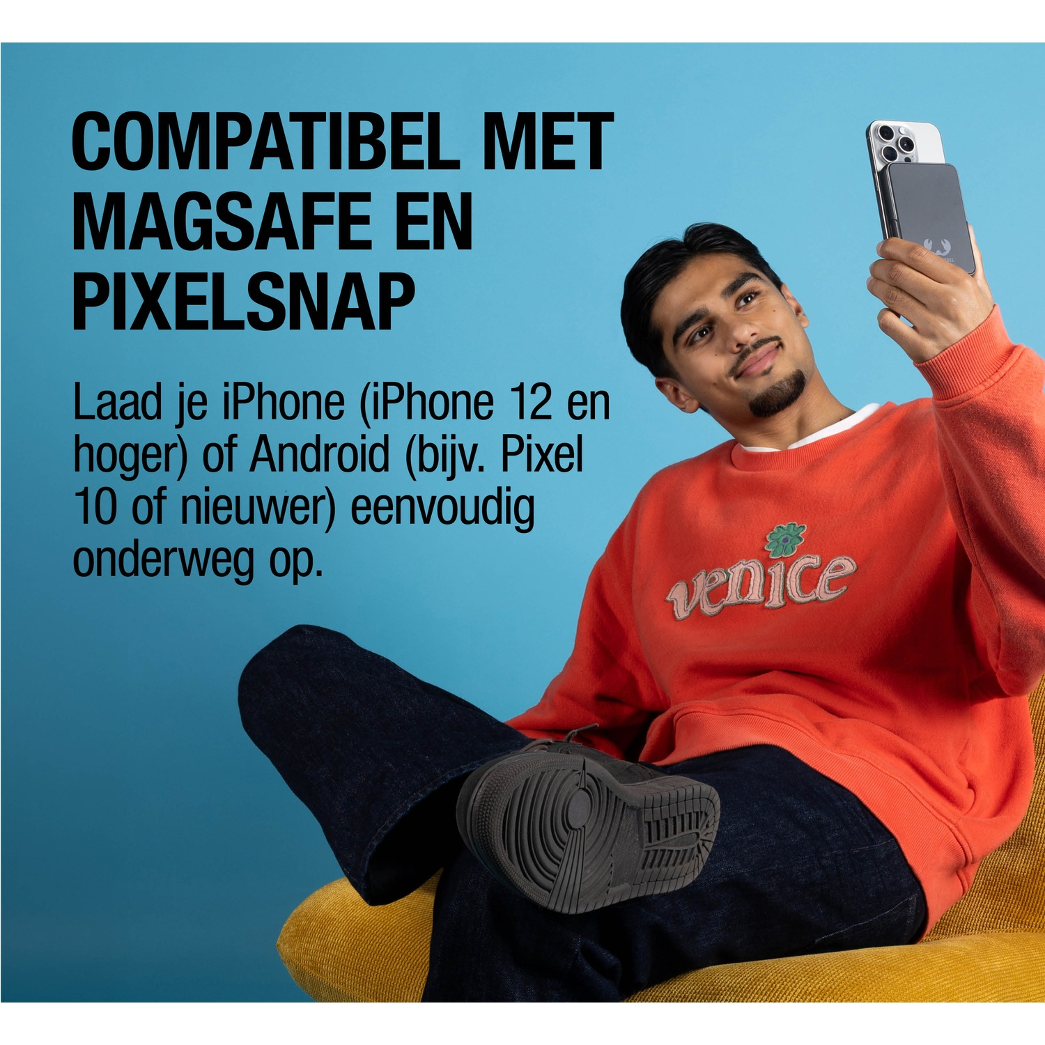 Man met telefoon houdt MagSafe lader vast voor blauwe achtergrond.