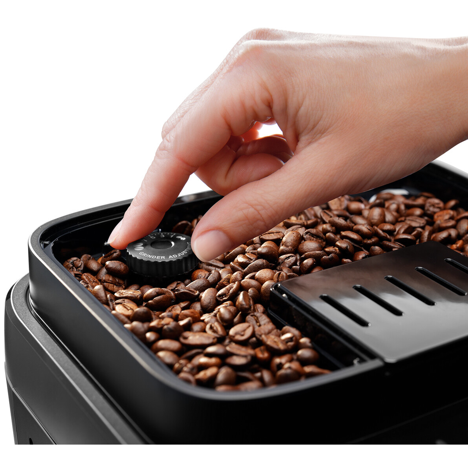 Een hand draait aan een zwarte instelknop boven geroosterde koffiebonen.