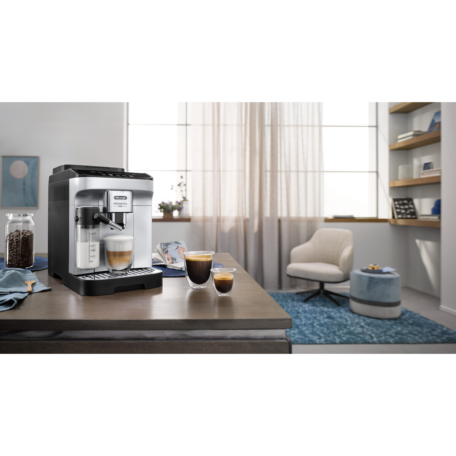 Een zwart-zilveren volautomatische koffiemachine met melkreservoir en twee espresso kopjes.