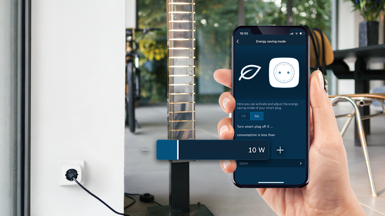 Hand hält Smartphone mit Energiesparmodus-App. Steckdose im Hintergrund.