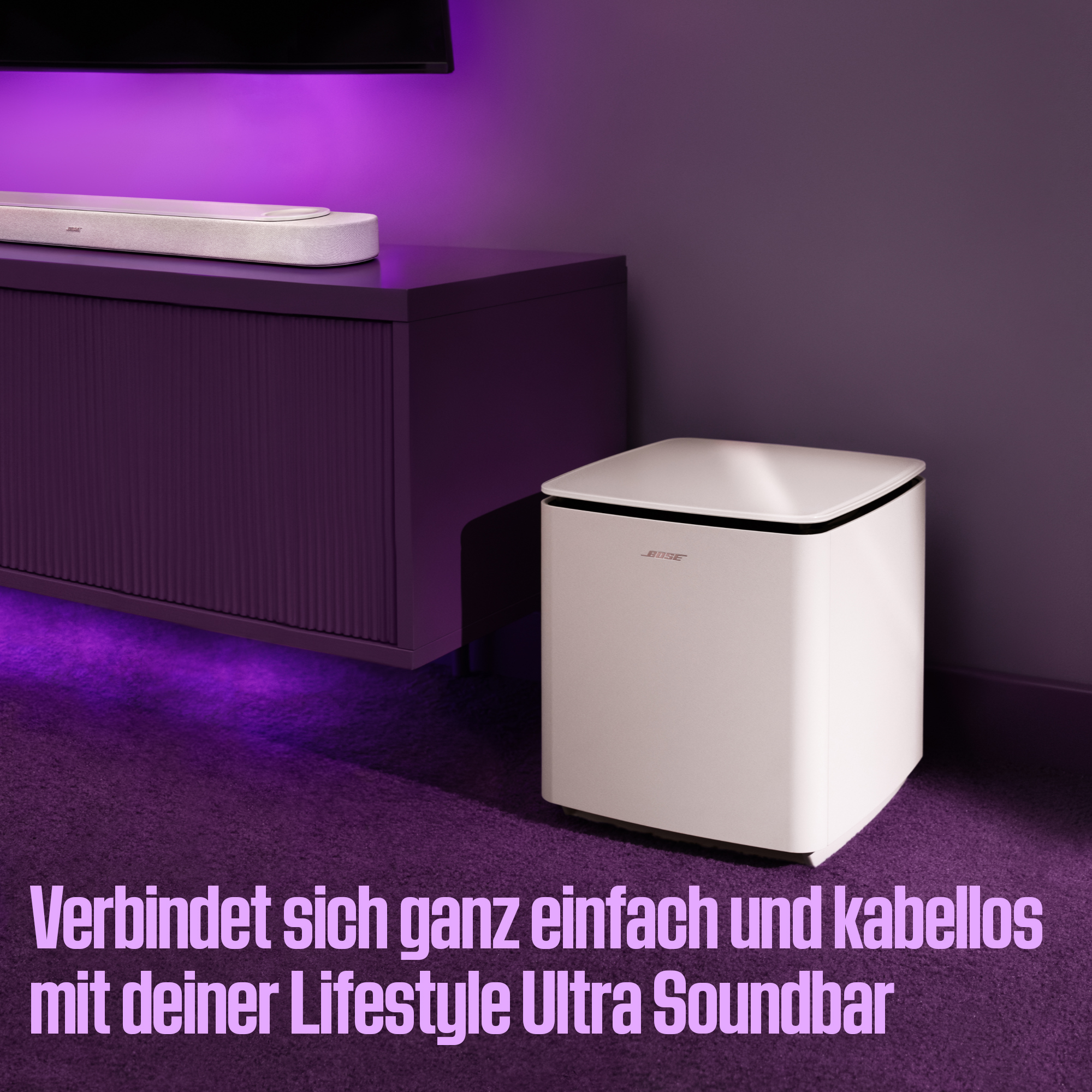 Weiße Bose Soundbar und Subwoofer auf lila Möbeln mit violetter Beleuchtung.