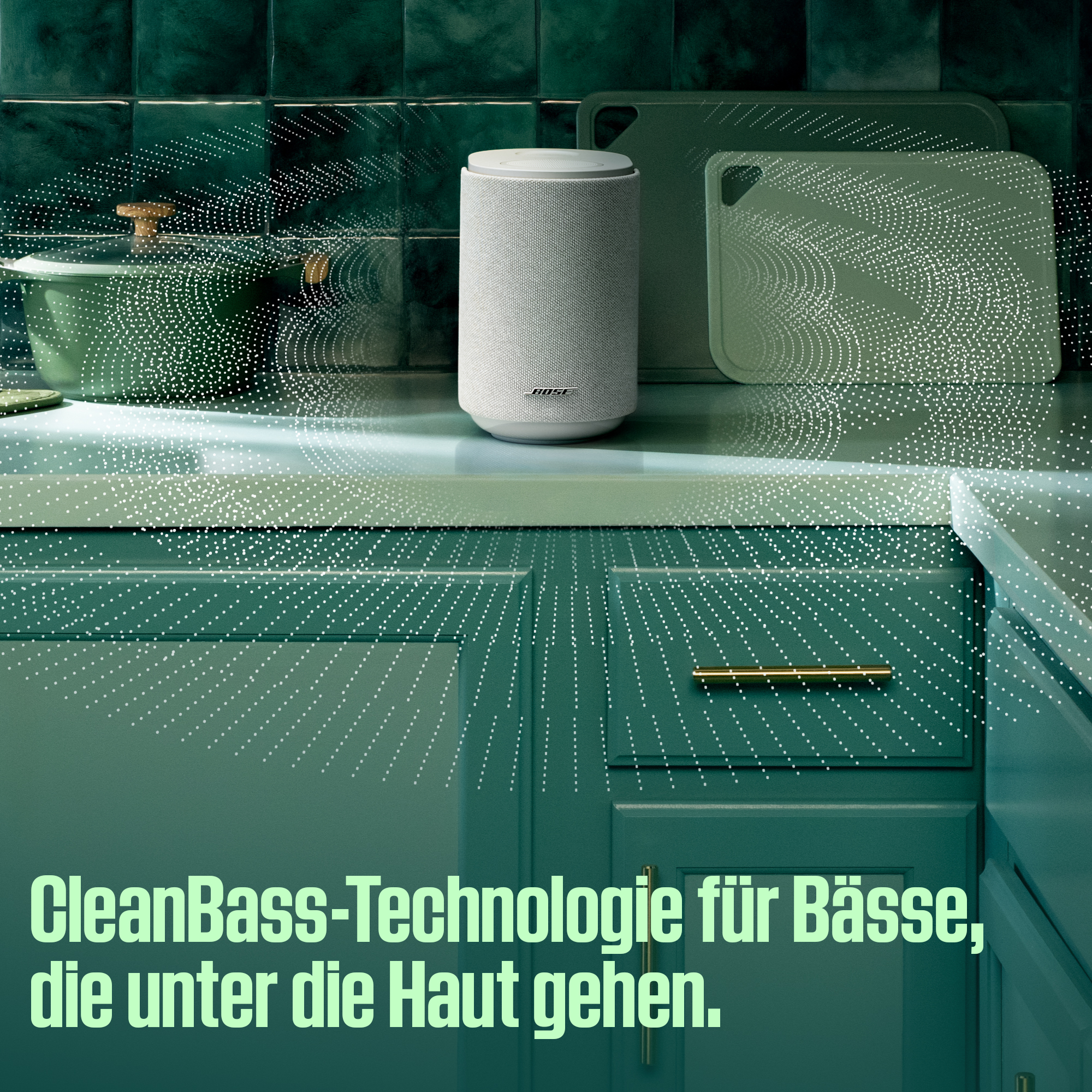 Ein weißer Bose Lautsprecher steht auf einer Küchenarbeitsplatte neben einem Topf.