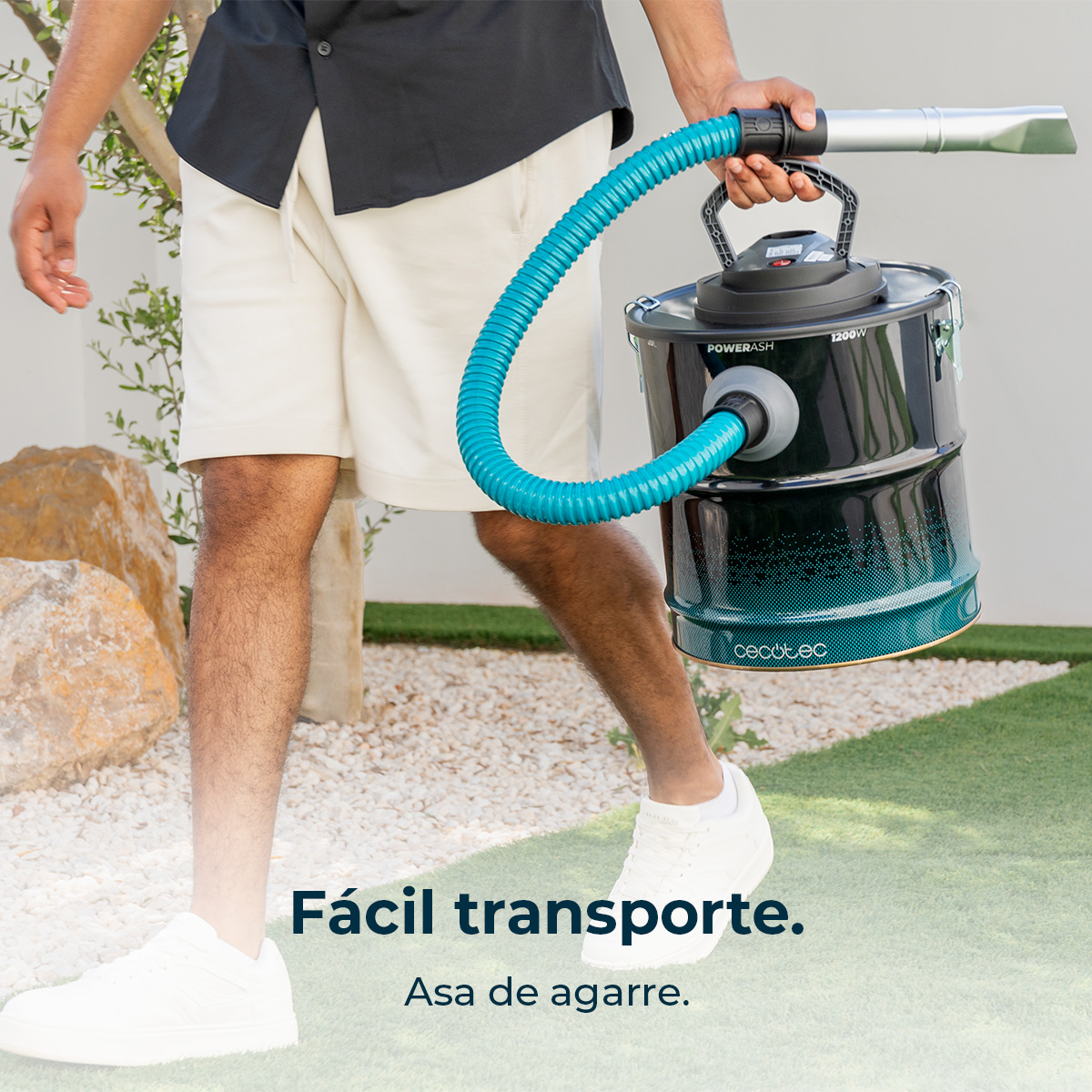 Hombre porta aspiradora negra con manguera azul, al aire libre.