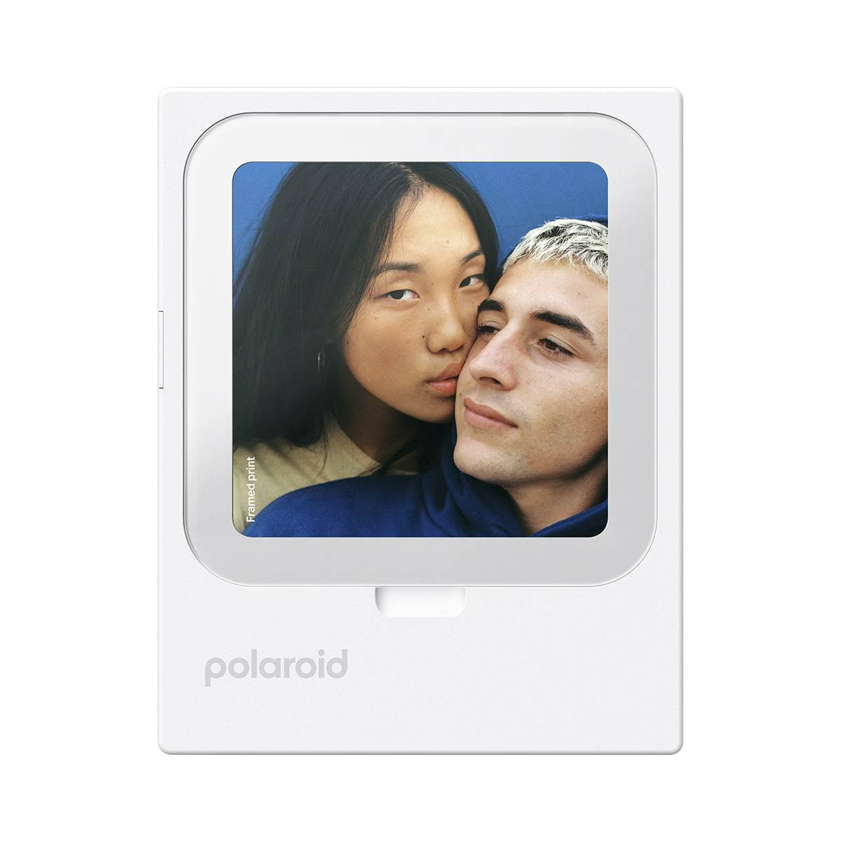 Un hombre y una mujer se acurrucan frente a un fondo azul en una foto Polaroid.