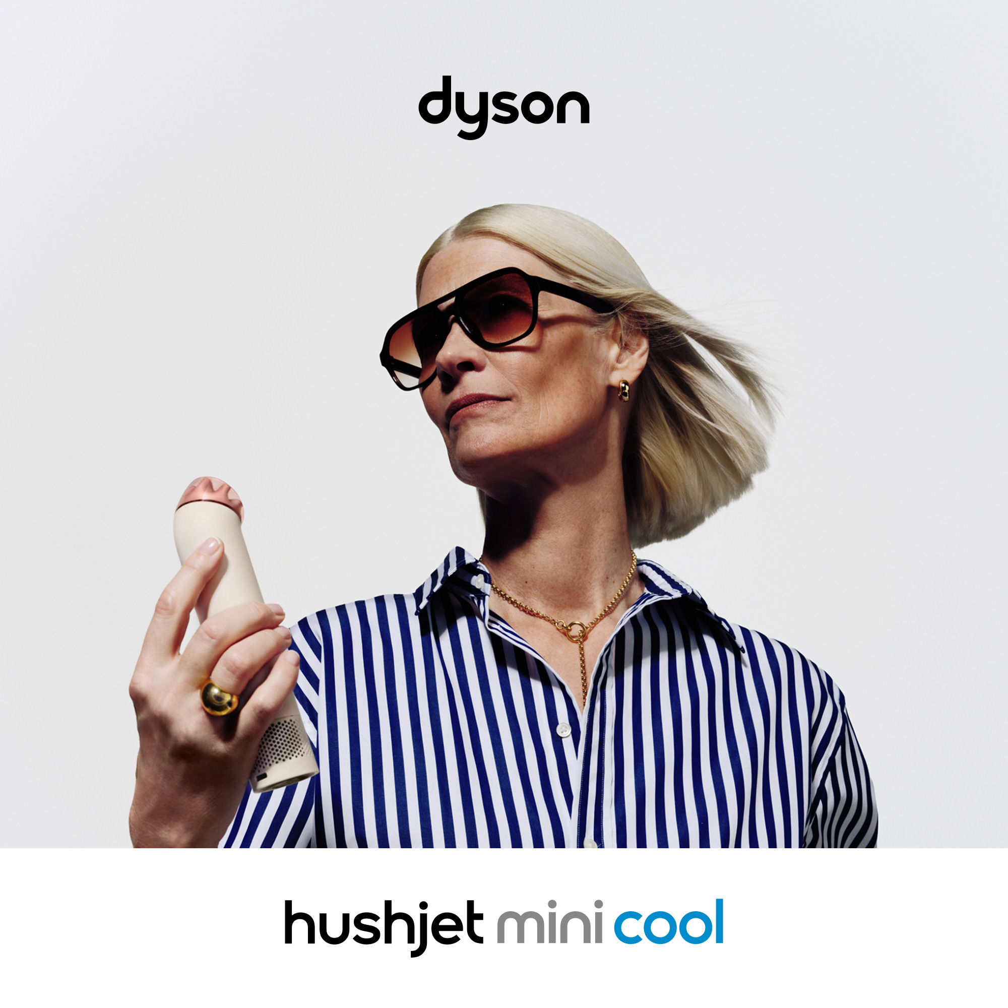 Mujer con gafas de sol y collar sostiene un dispositivo Dyson.