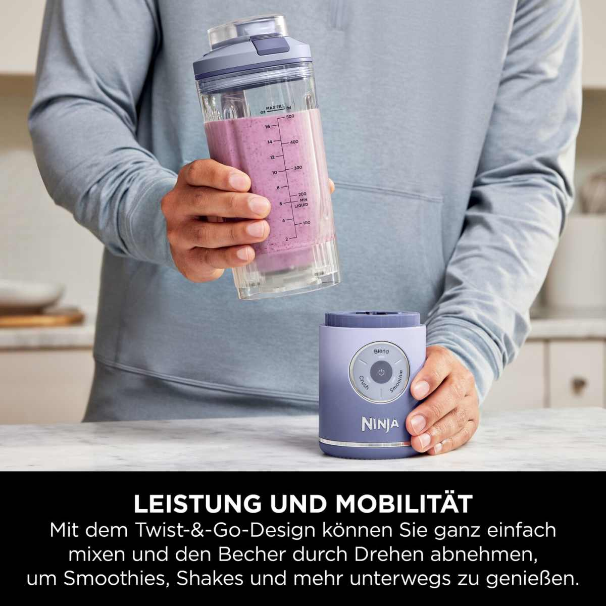 Une main tient une tasse à smoothie au-dessus d'un mixeur Ninja violet.