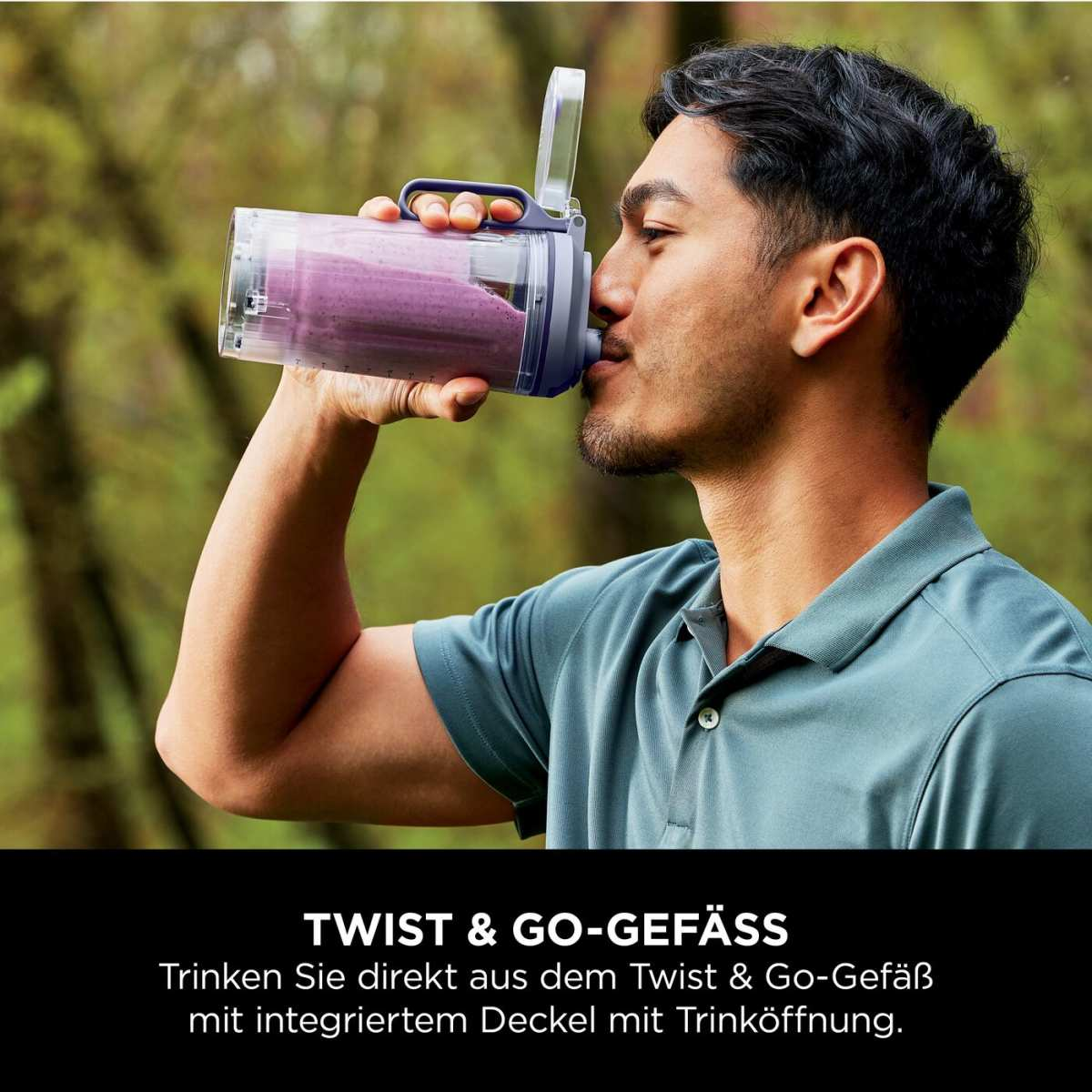 Un homme boit un smoothie violet dans un récipient transparent en extérieur.