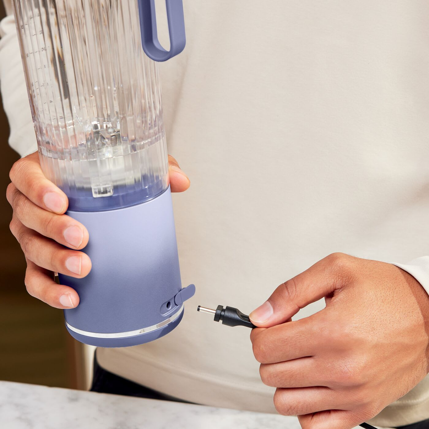 Une personne branche un câble de chargement à un mixeur portable.