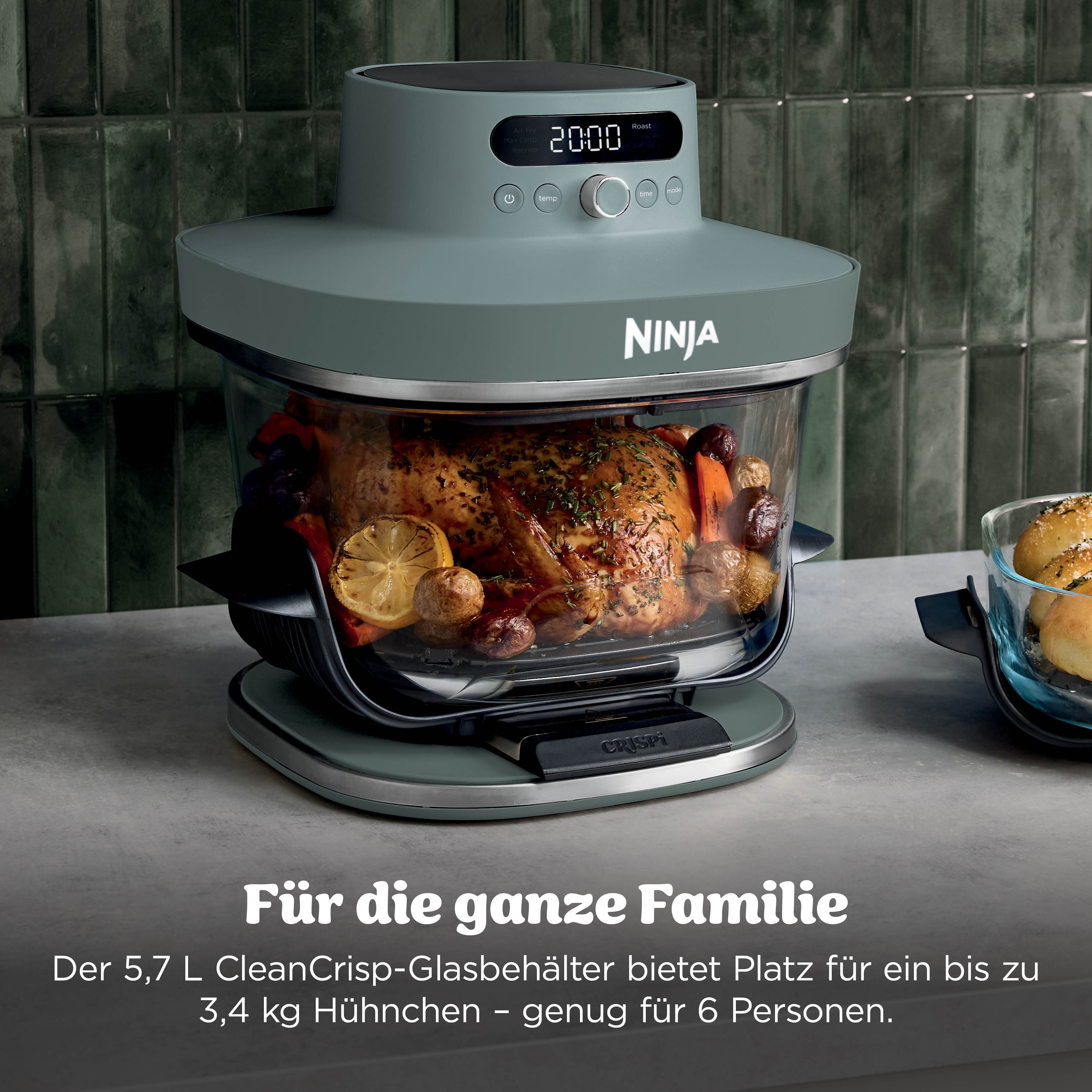Ein gebratenes Huhn mit Gemüse in einem Ninja-Ofen, daneben Brötchen.