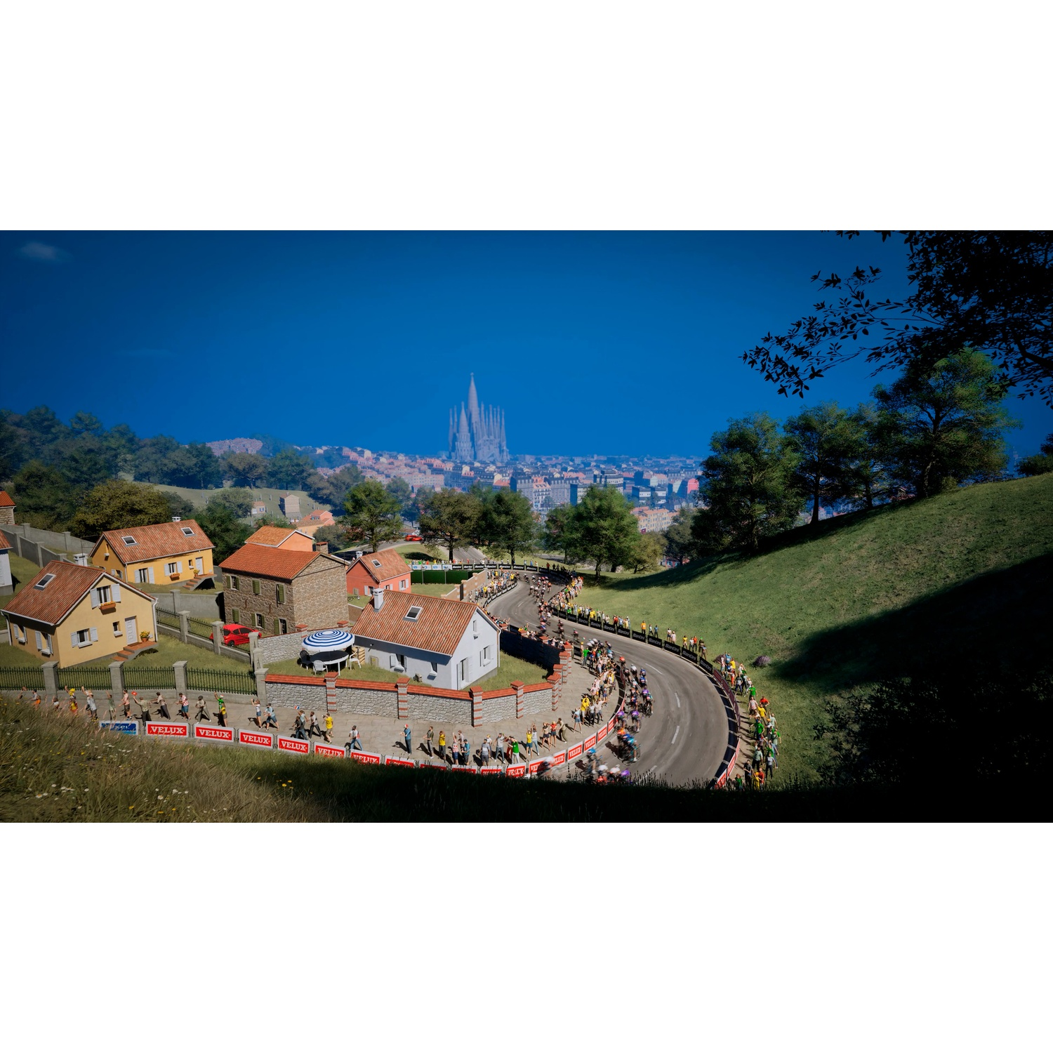 Cyclists on a winding road in front of houses and a city skyline with a tower.