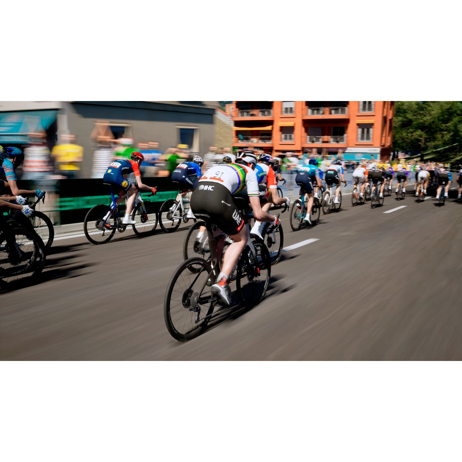 Cyclists race in a pack on a road with buildings in the background.