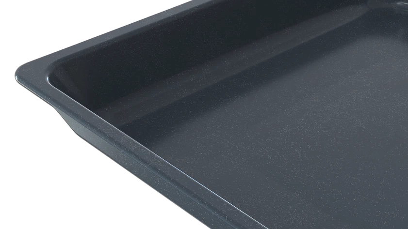 Una bandeja para hornear rectangular y oscura con bordes ligeramente elevados, sobre negro.
