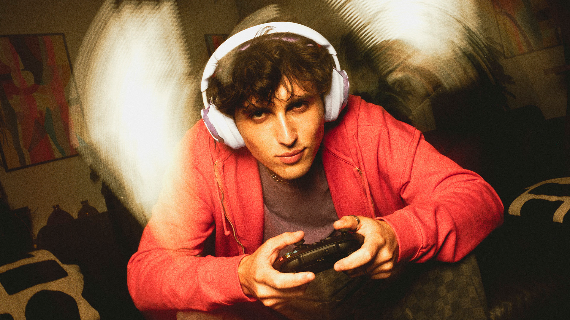 Un jeune homme avec un casque joue à des jeux vidéo dans une pièce sombre.