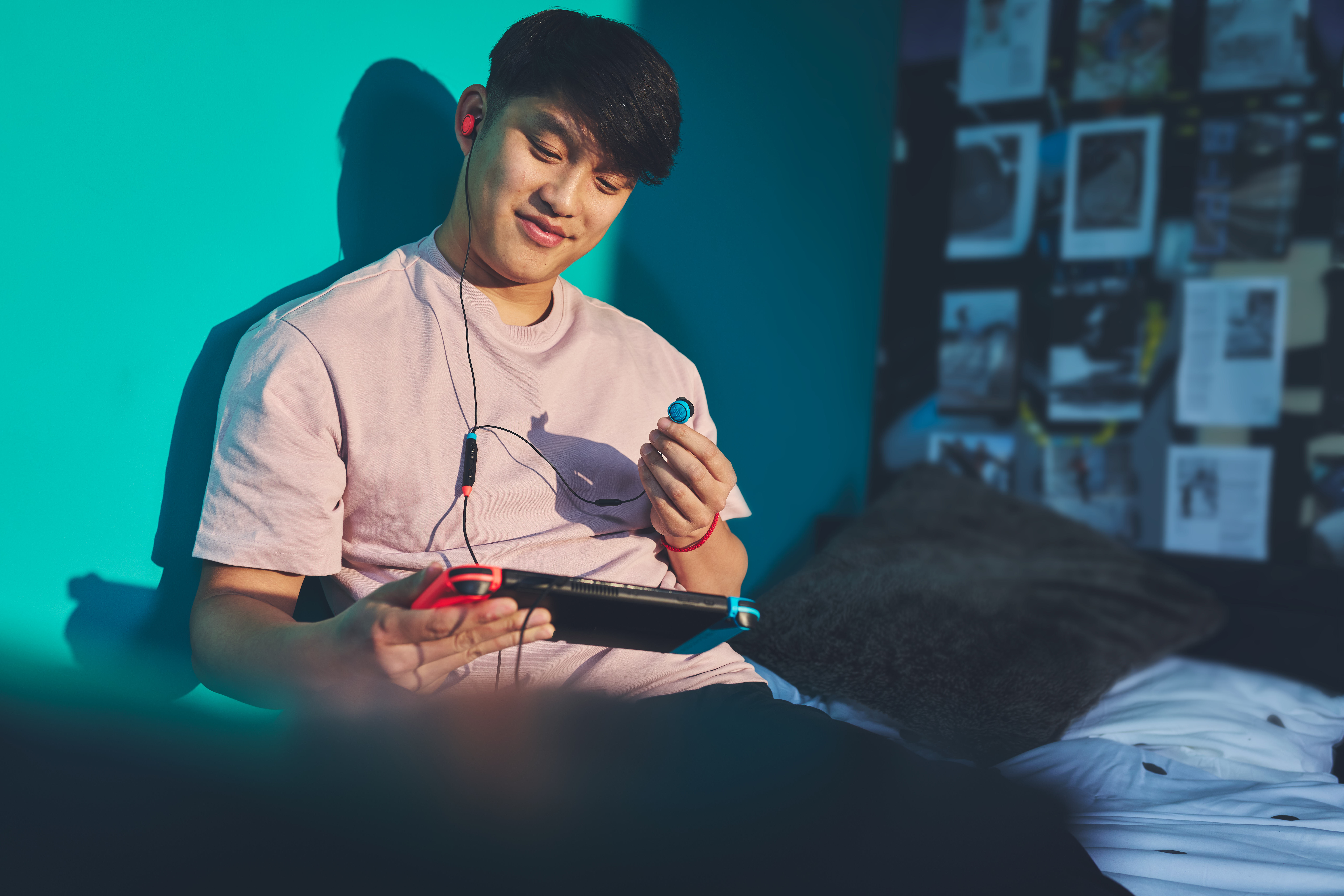 Un jeune homme avec des écouteurs joue sur une console portable.