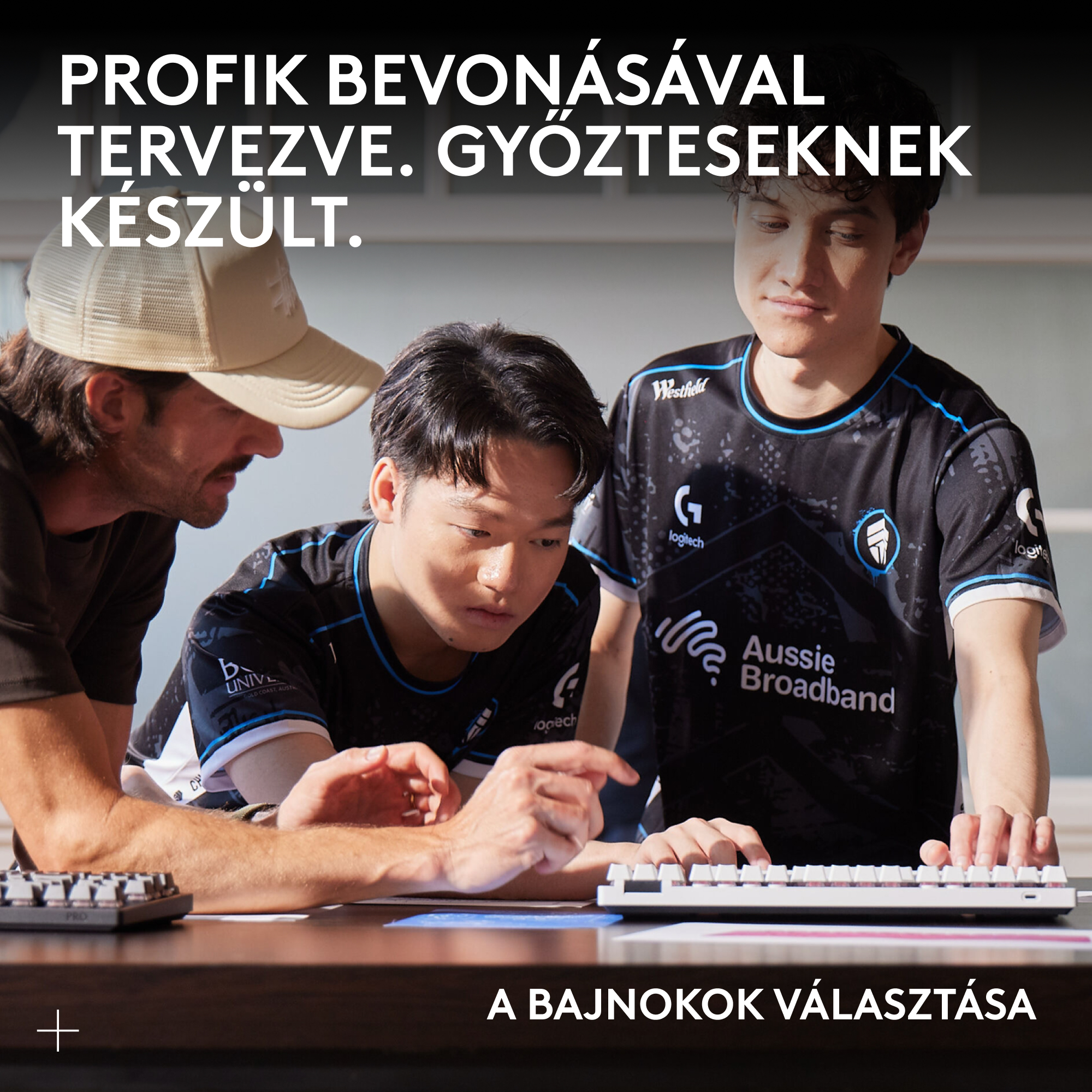 Három fiatal férfi gamer mezben néz egy billentyűzetet és egeret.