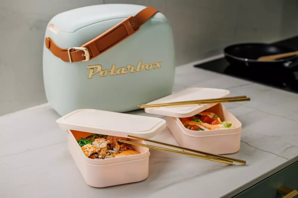 Jasnoniebieska lodówka Polarbox z dwoma otwartymi pudełkami na lunch wypełnionymi jedzeniem i pałeczkami.