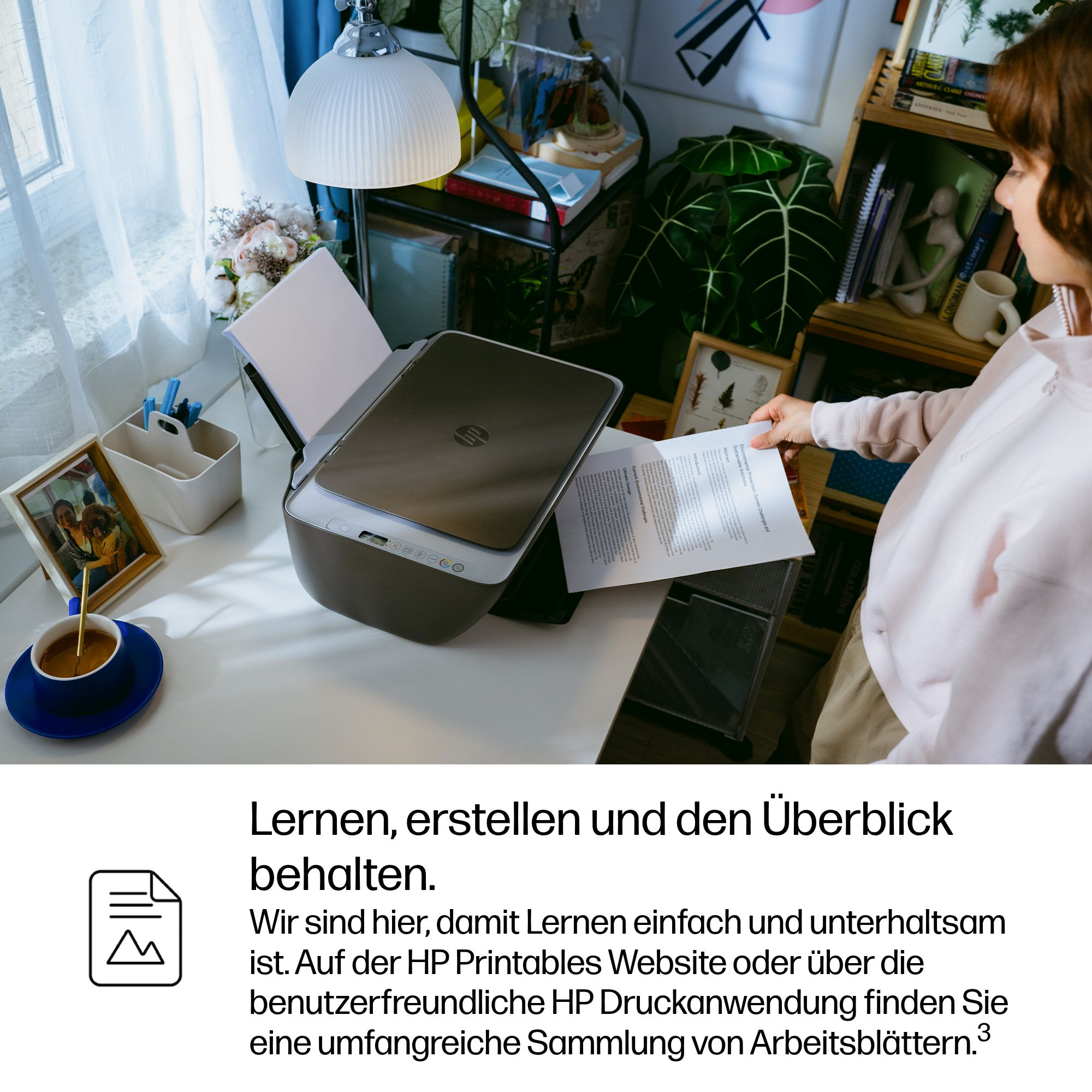 Eine Frau hält ein Dokument neben einem Drucker. Ein Kaffeebecher steht auf dem Tisch.