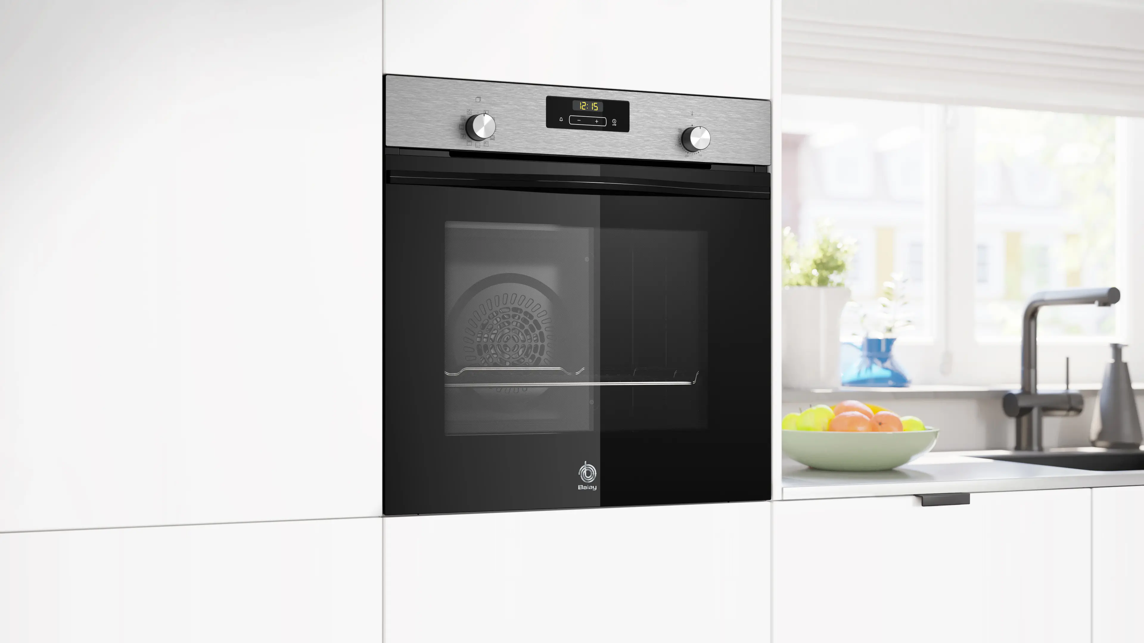 Horno empotrado moderno con detalles de acero inoxidable y puerta de cristal junto a frutero.