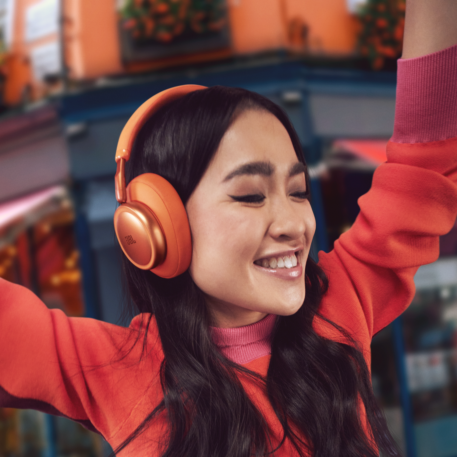 Young woman wearing orange headphones and red sweater is dancing.