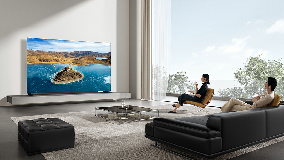 Egy pár pihen egy modern nappaliban, a TV képernyőjén tájkép látható.