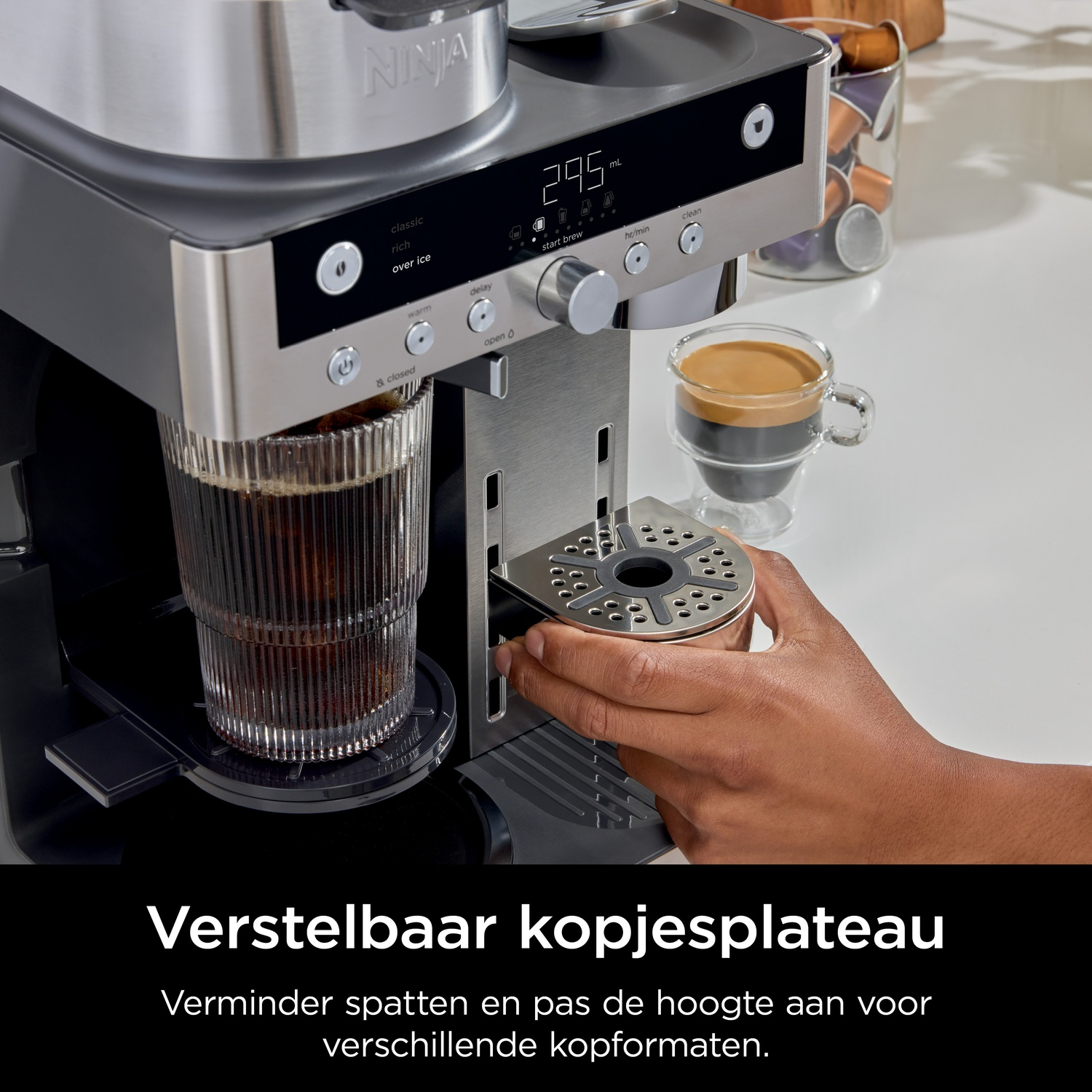 A hand adjusts the height-adjustable drip tray on a coffee machine.