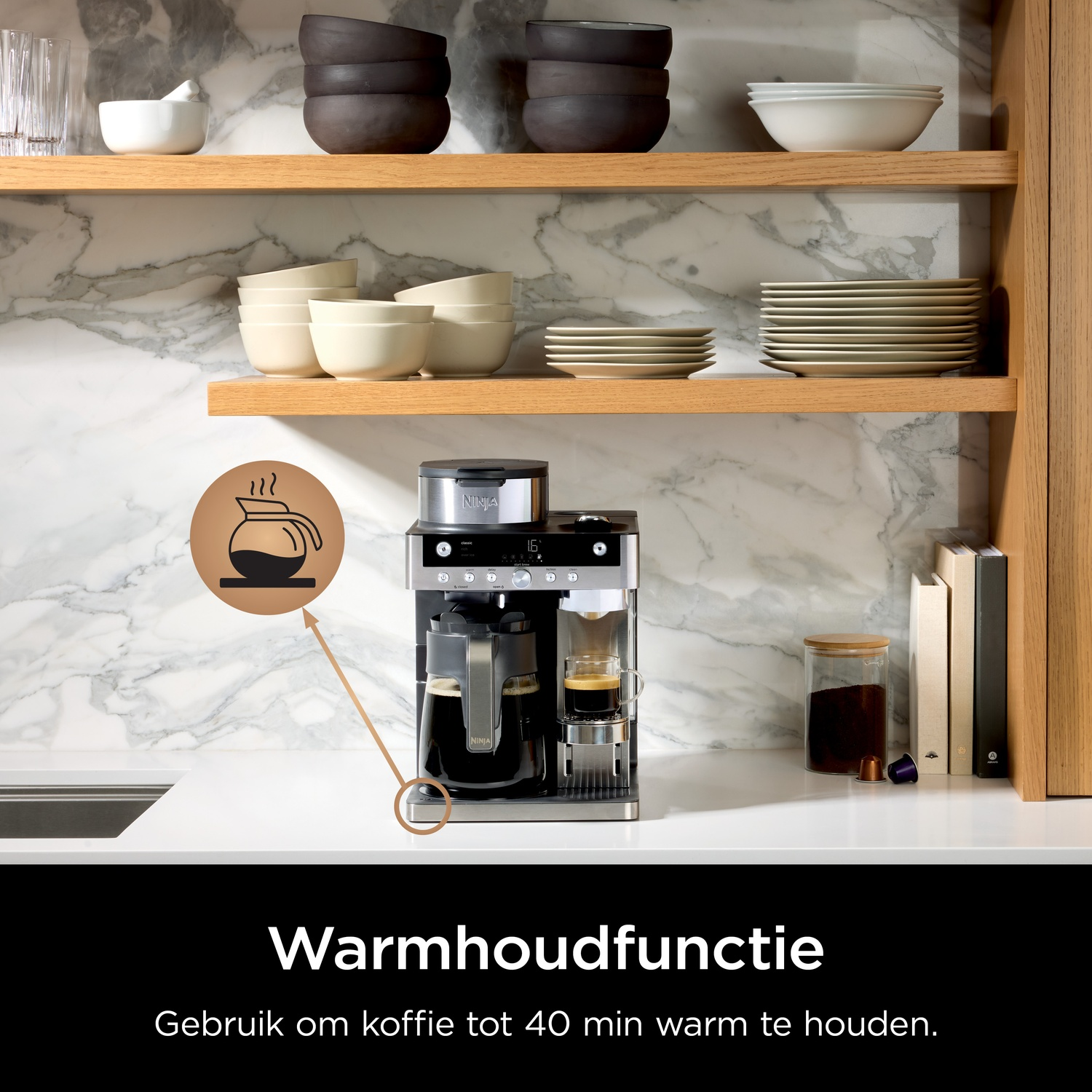A coffee maker with a carafe and cups on a shelf with a marble background.