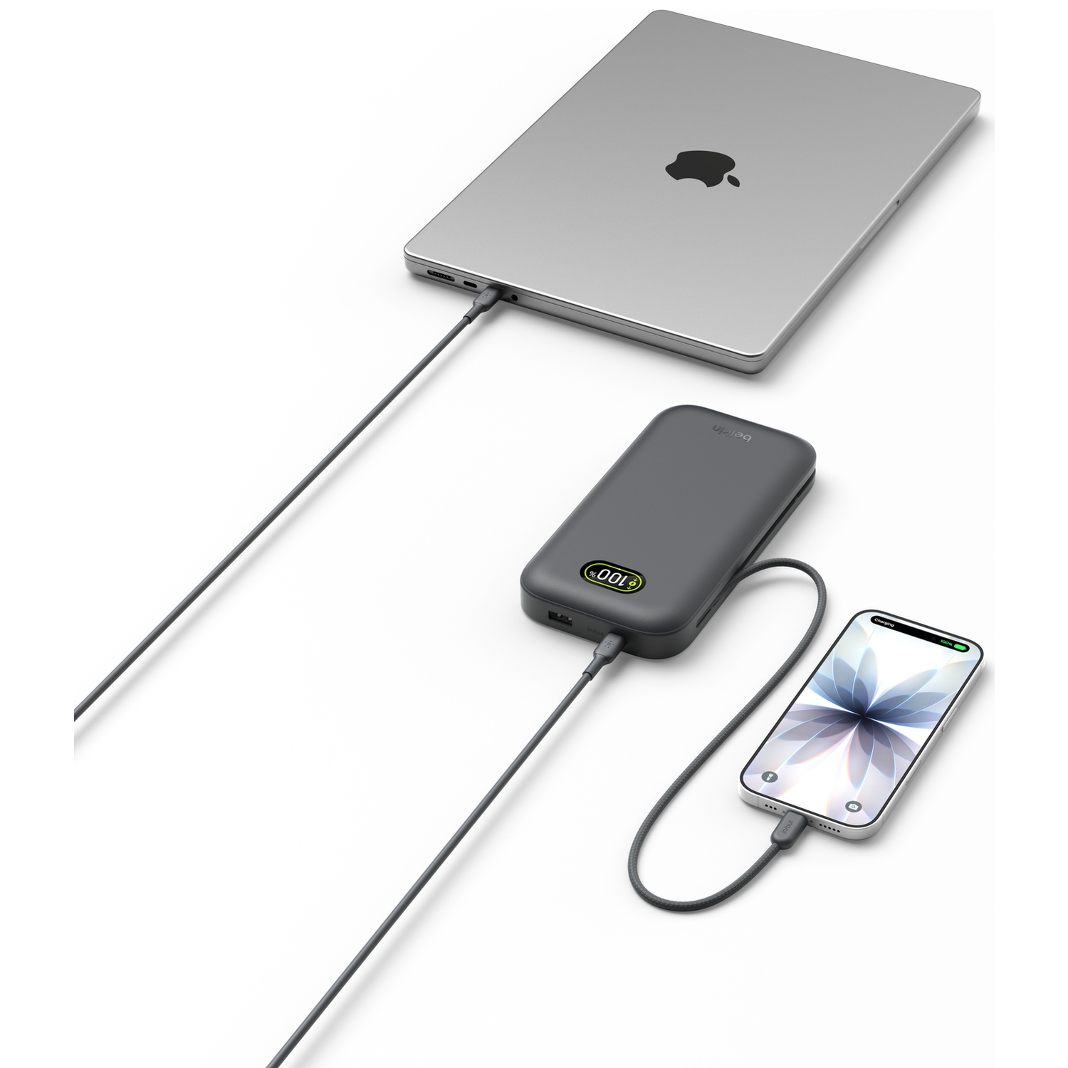 MacBook gris, batterie externe et smartphone connectés par câbles.