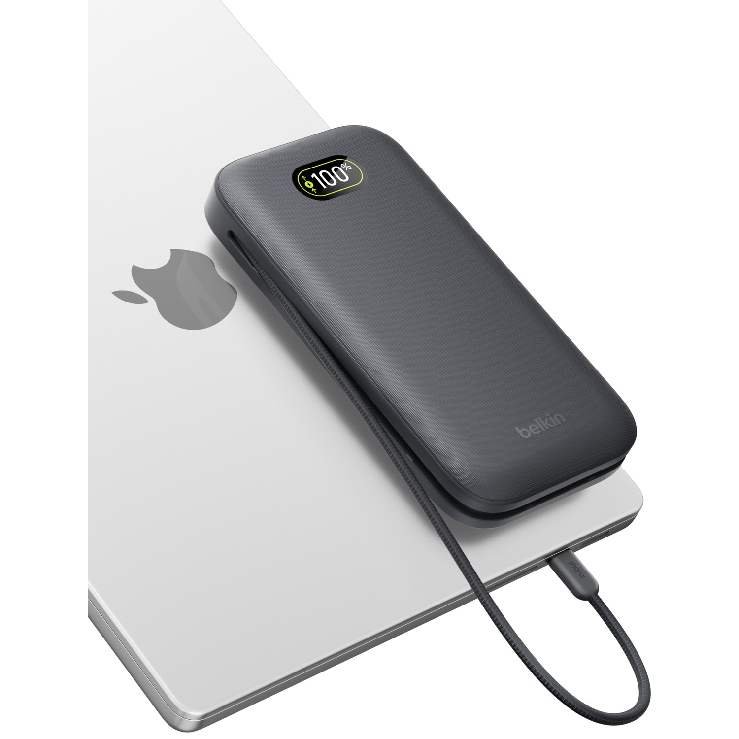 Une batterie externe Belkin grise à 100% de charge est posée sur un ordinateur portable argenté.