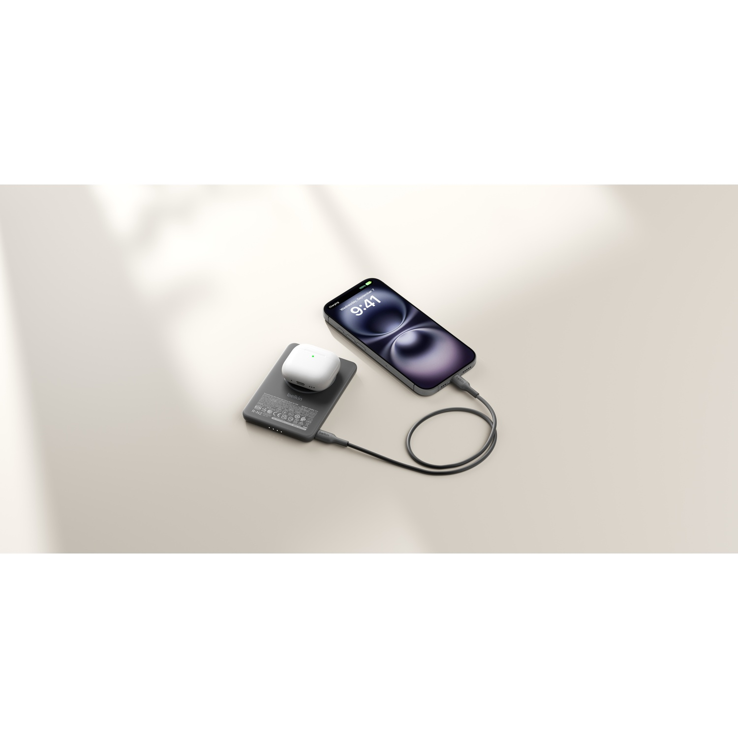 Un iPhone se charge via un câble, avec un étui de chargement sur une banque d'alimentation.