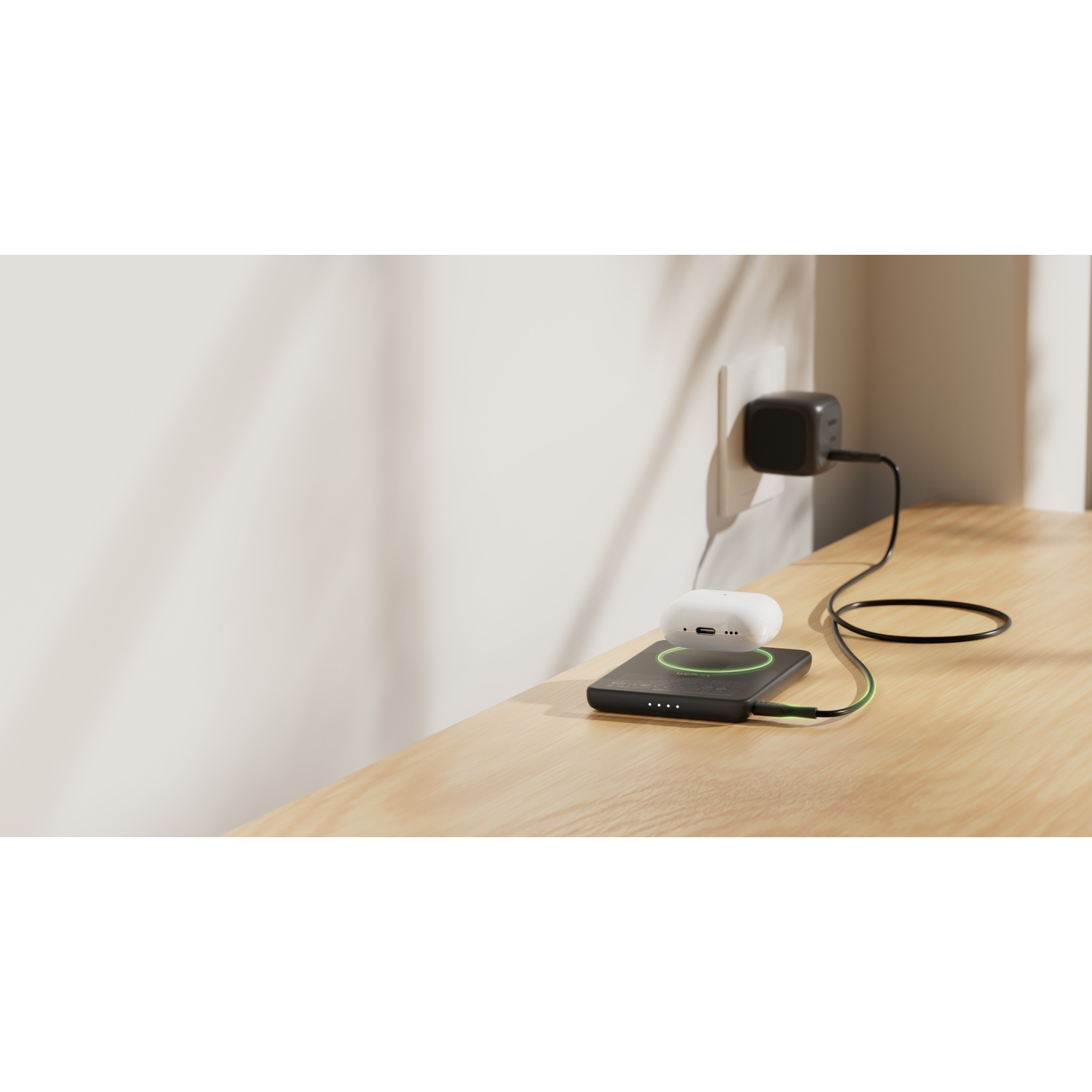 Un étui de chargement blanc repose sur un chargeur noir branché au mur.