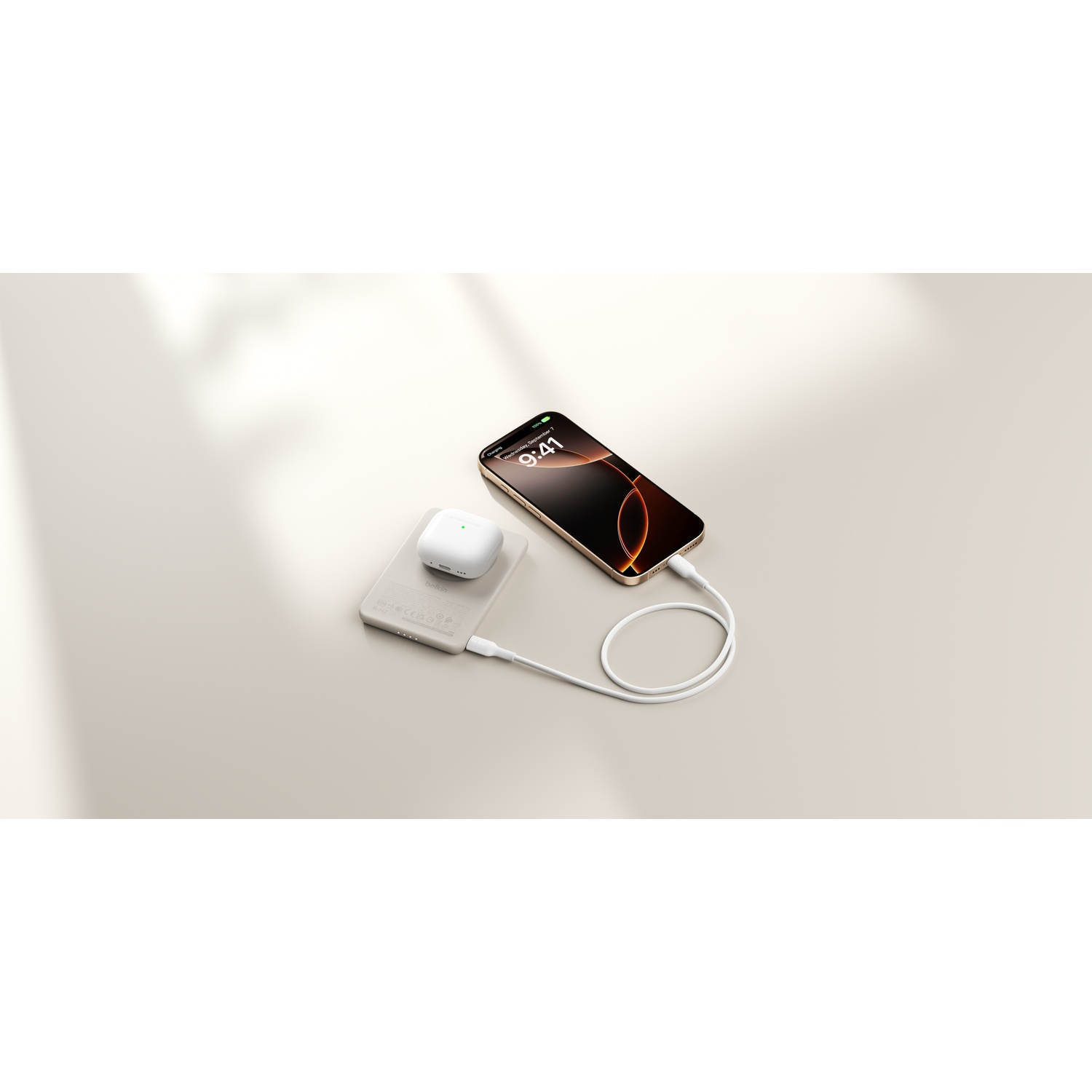 Un chargeur sans fil blanc avec un étui d'écouteurs et un téléphone en charge.