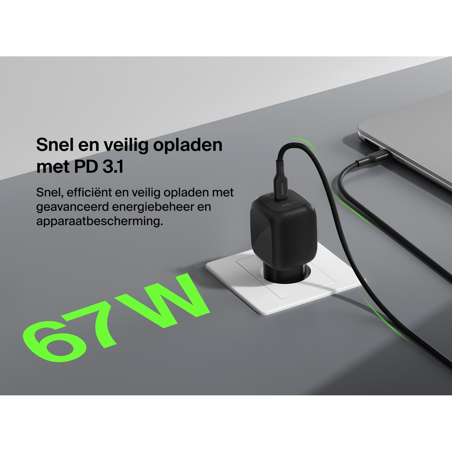 Chargeur noir branché, charge un ordinateur portable. 67W.