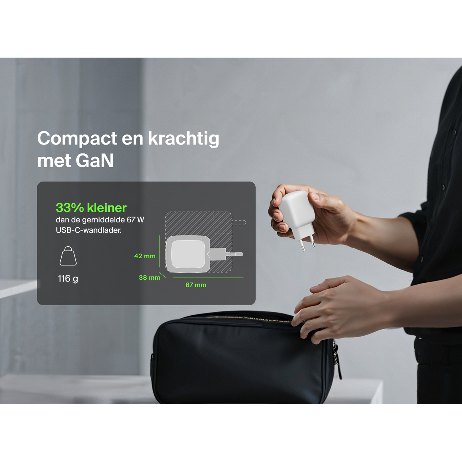 Une main tient un chargeur GaN blanc au-dessus d'un sac noir.
