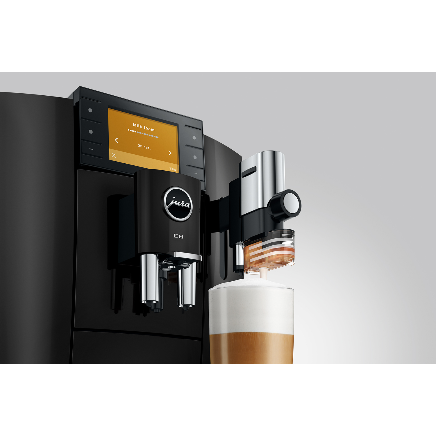 Zwarte Jura E8 koffiemachine schuimt melk in een glas koffie.