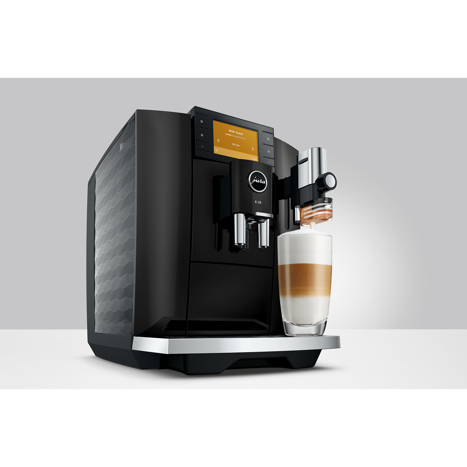 Een zwarte koffiezetapparaat met een glas latte macchiato.