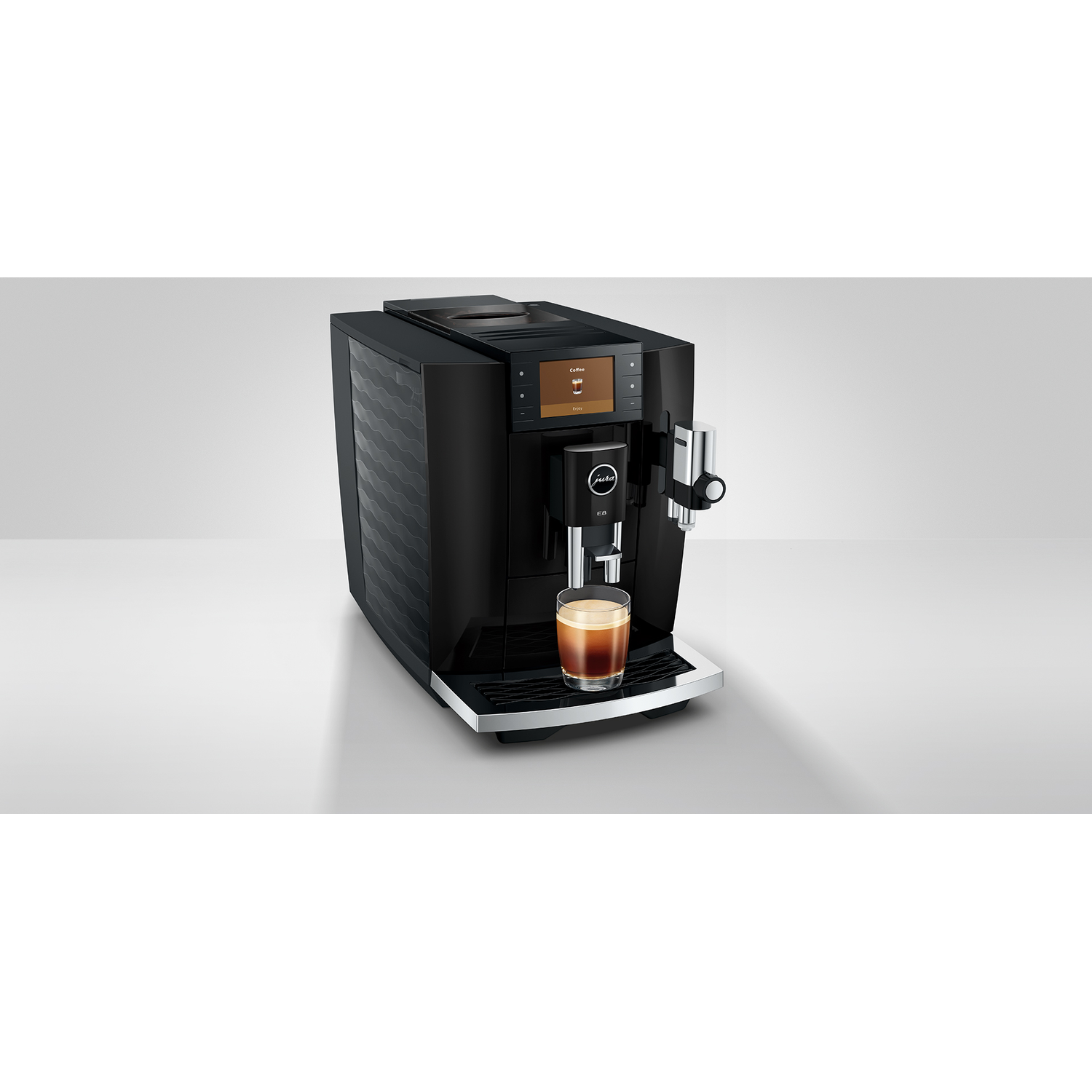 Zwarte Jura volautomatische koffiemachine met een glas espresso en schuim.