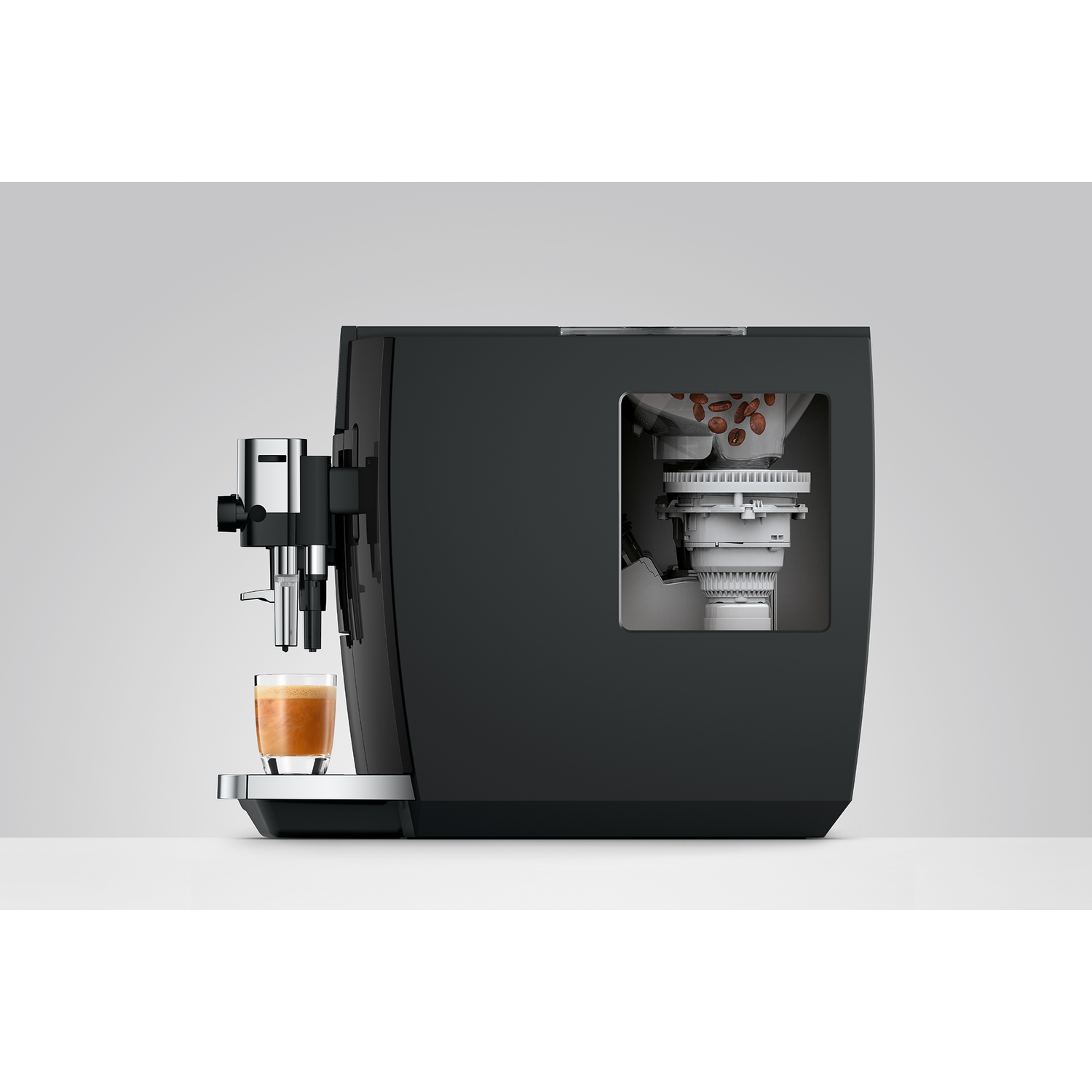 Zwarte koffiemachine met glas espresso en zichtbare koffiebonen binnenin.