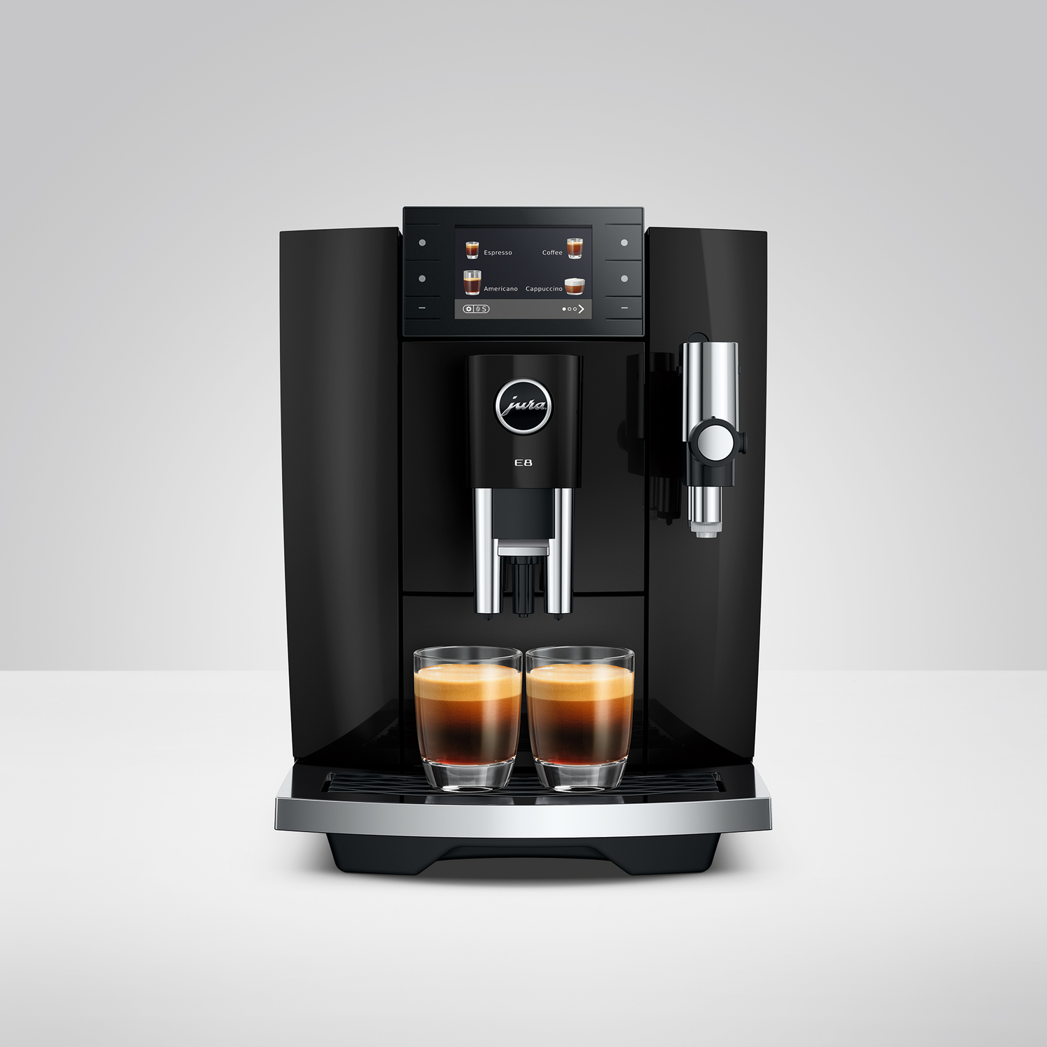 Een zwarte Jura koffiemachine met twee glazen espresso op de lekbak.