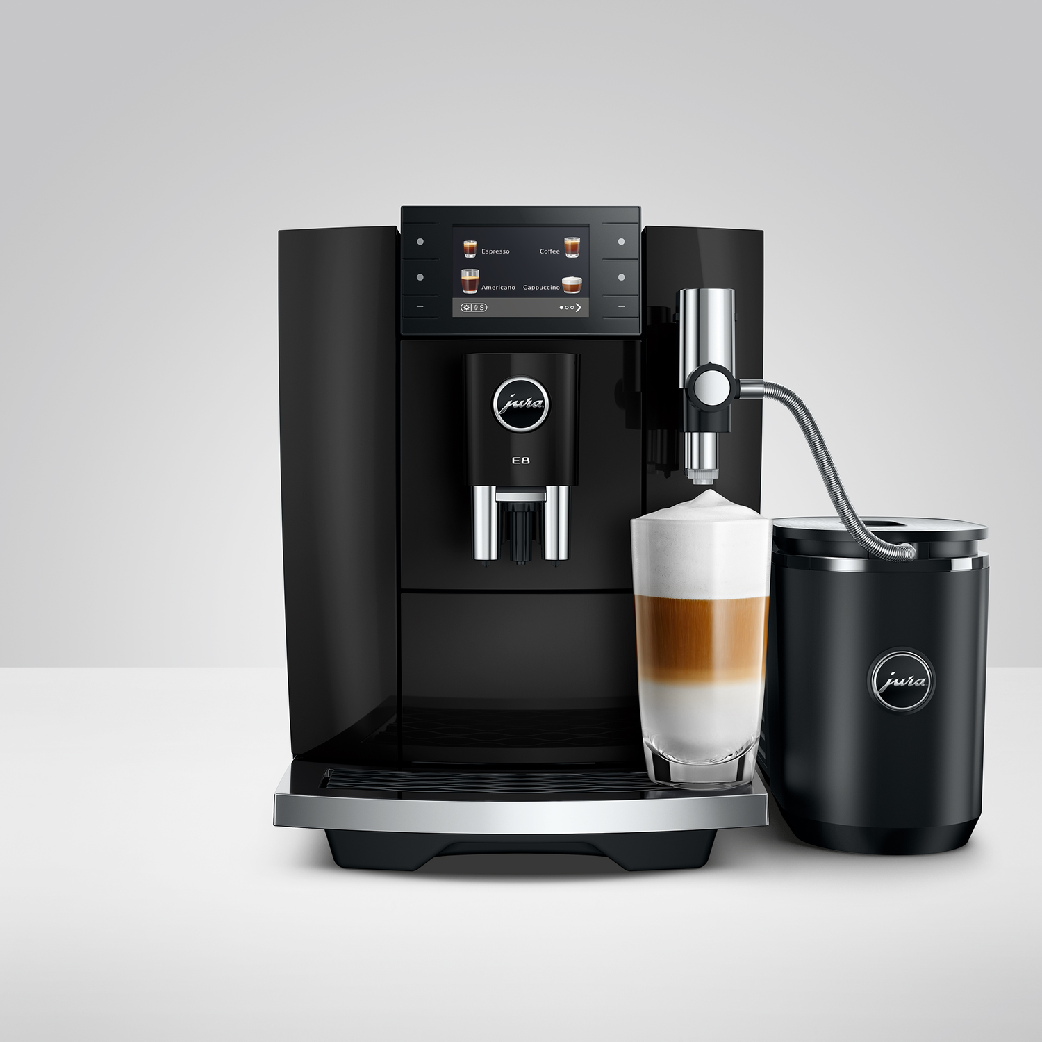 Zwarte koffiemachine met melkkan en een gelaagde koffiedrank.