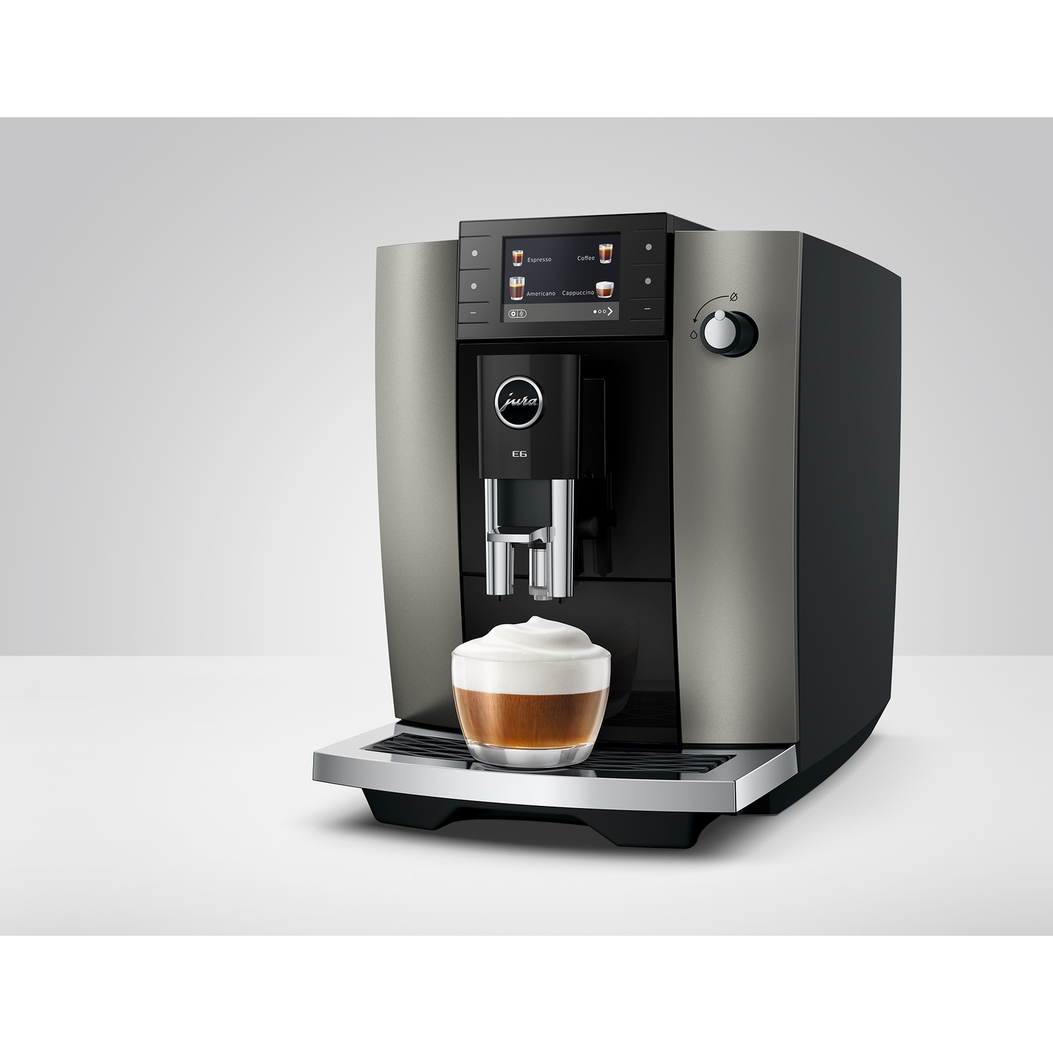 Een zilveren Jura koffiezetapparaat met een glas schuimige koffie.