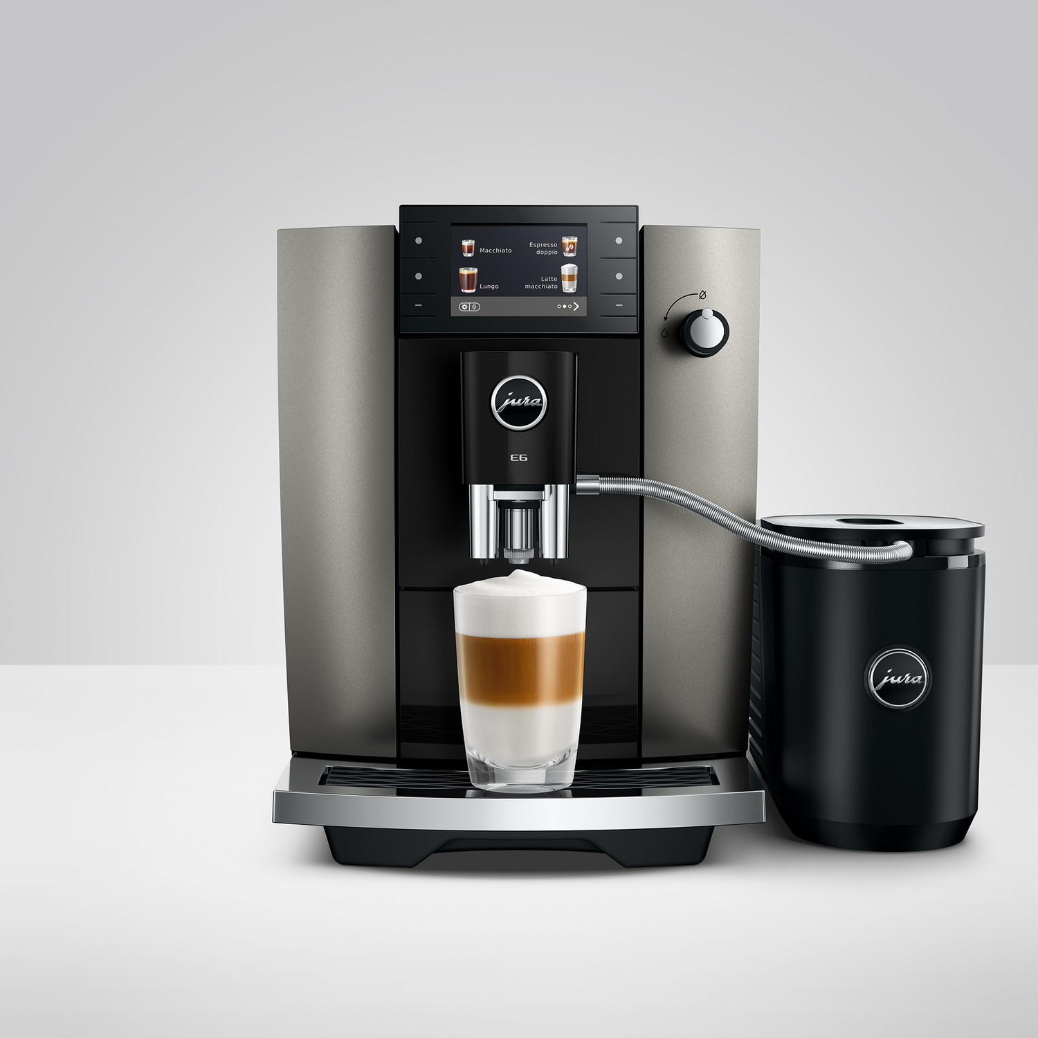 Een Jura koffiemachine met melkschuim in een glas en een melkcontainer.