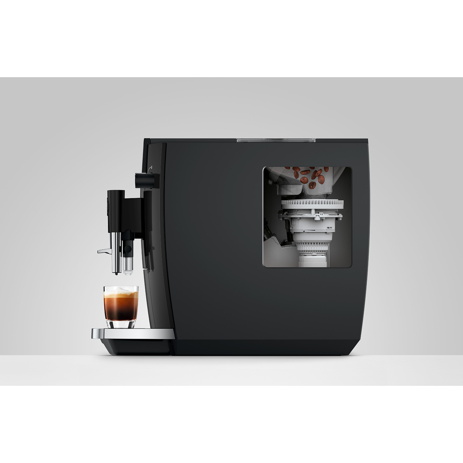 Zwarte koffiemachine met espressoglas en zichtbare bonenhouder.