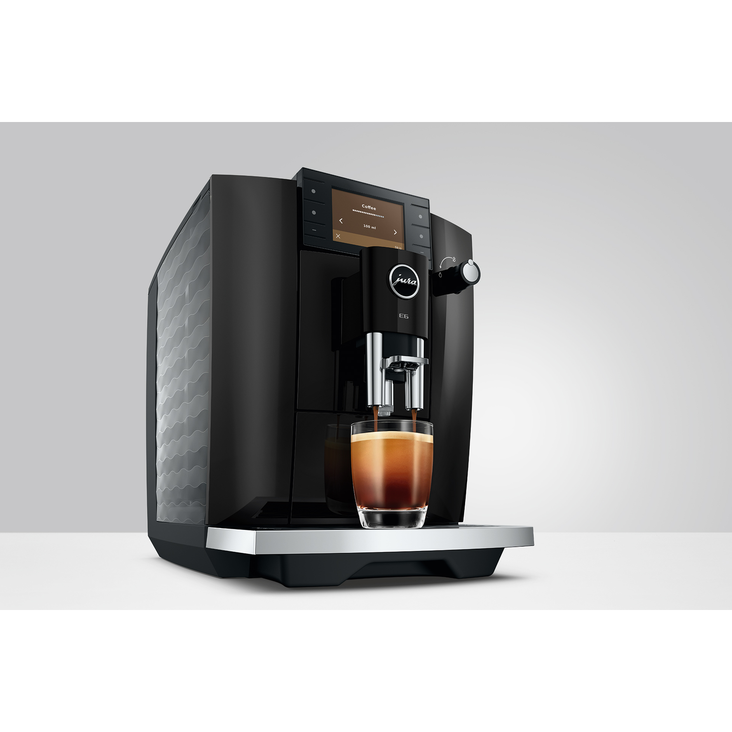 Zwarte koffiemachine zet espresso in een glas op een zilveren lekbak.