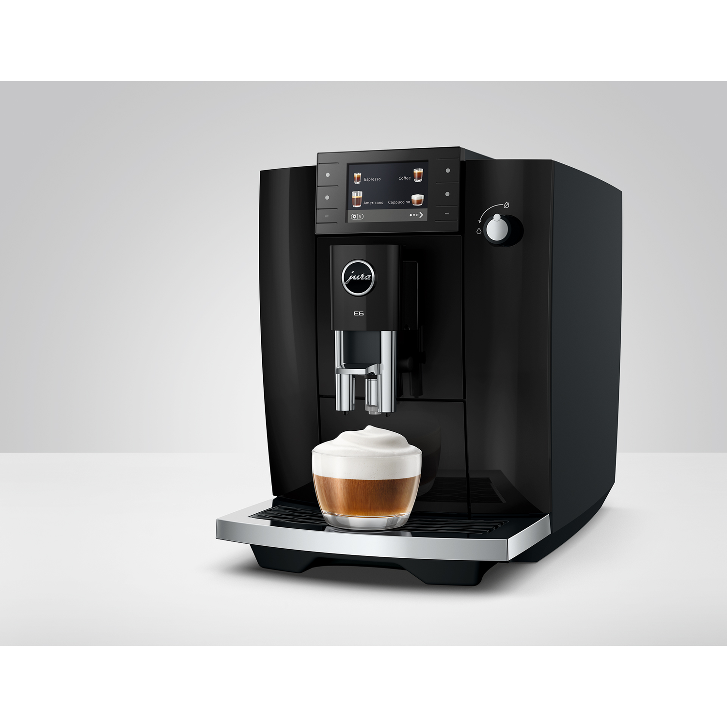 Zwarte Jura koffiemachine met een glas koffie met melkschuim.